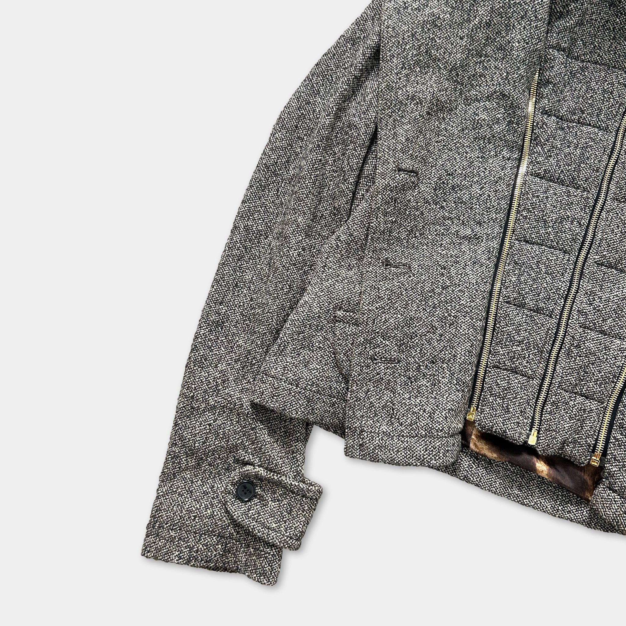A gray tweed jacket with a zipper and a small button on the sleeve.