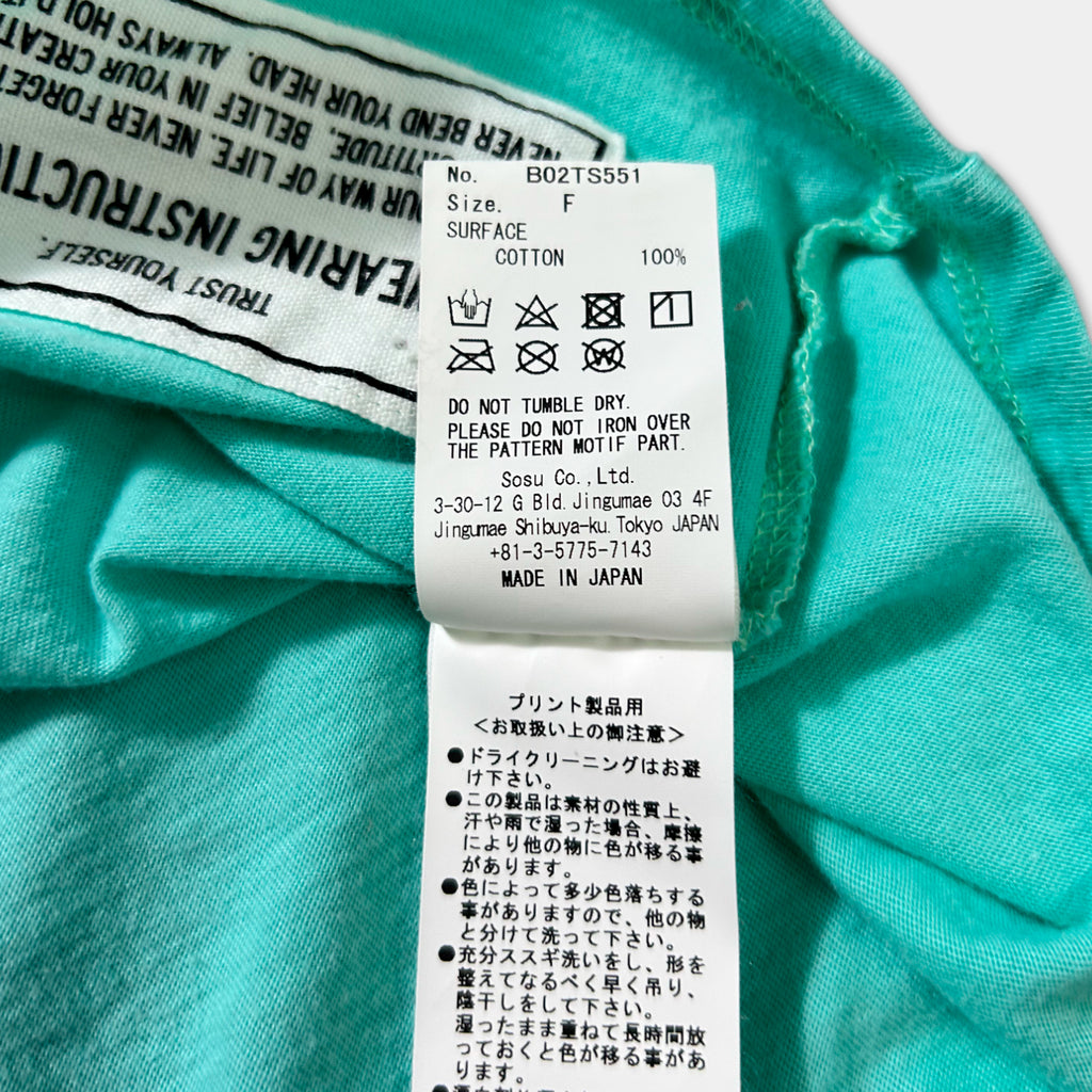 a close-up of a turquoise fabric with a label attached to it, which contains text in Japanese.