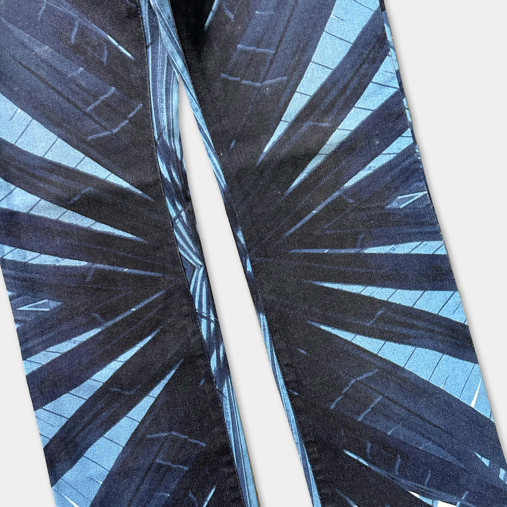 a pair of pants with a striking blue and black abstract pattern, featuring a repeating design of diagonal lines and geometric shapes.