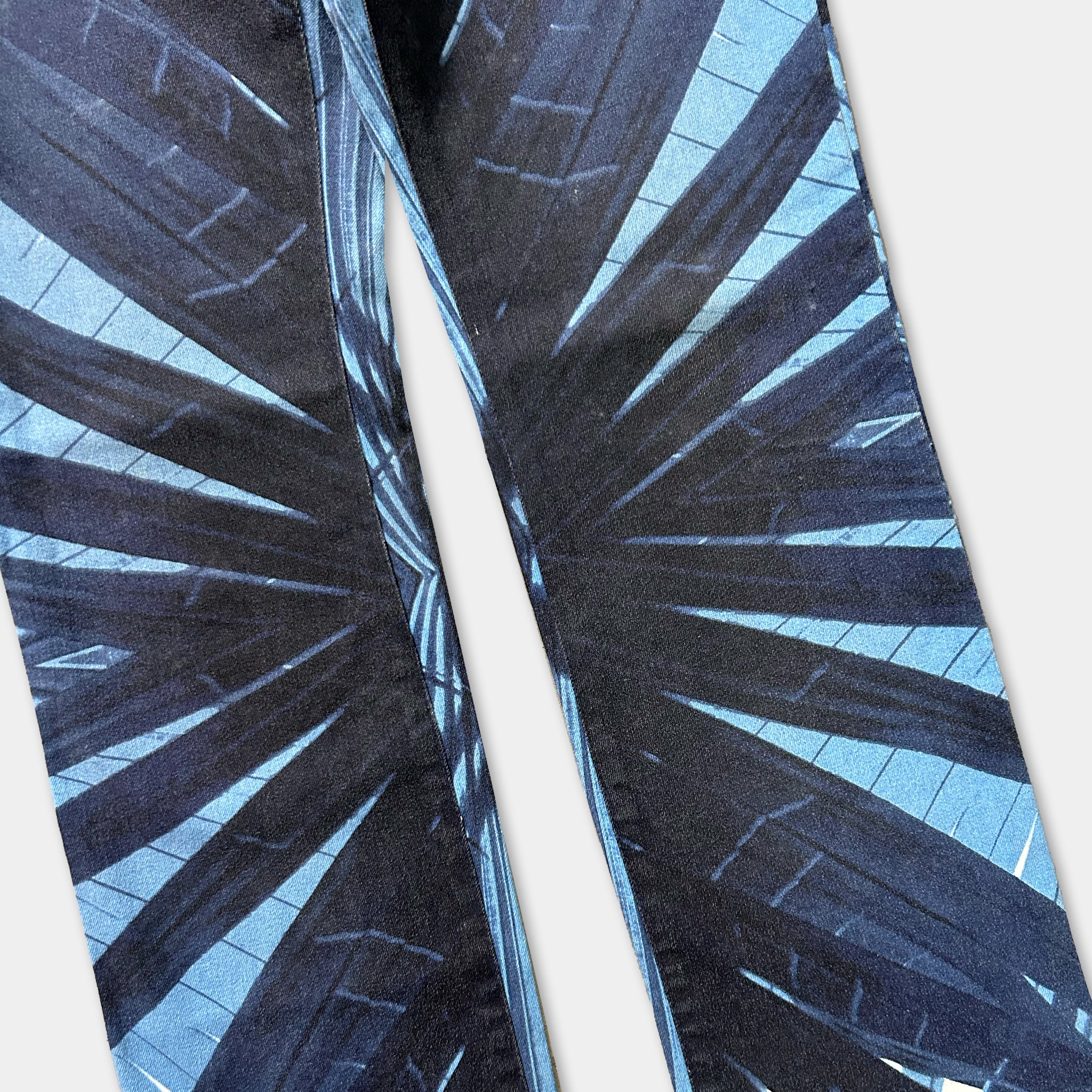 a pair of pants with a striking blue and black abstract pattern, featuring a repeating design of diagonal lines and geometric shapes.