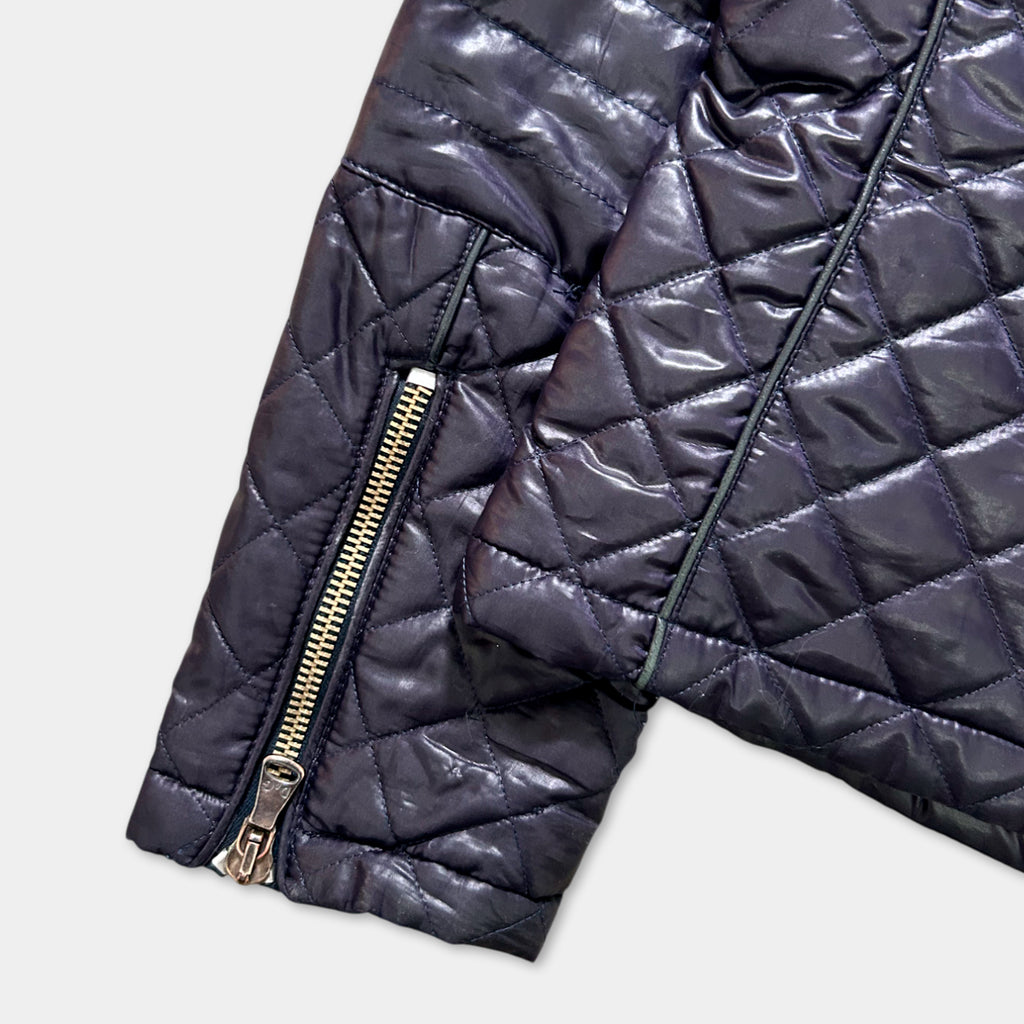 A close-up view of a dark quilted jacket with a zipper and pockets.