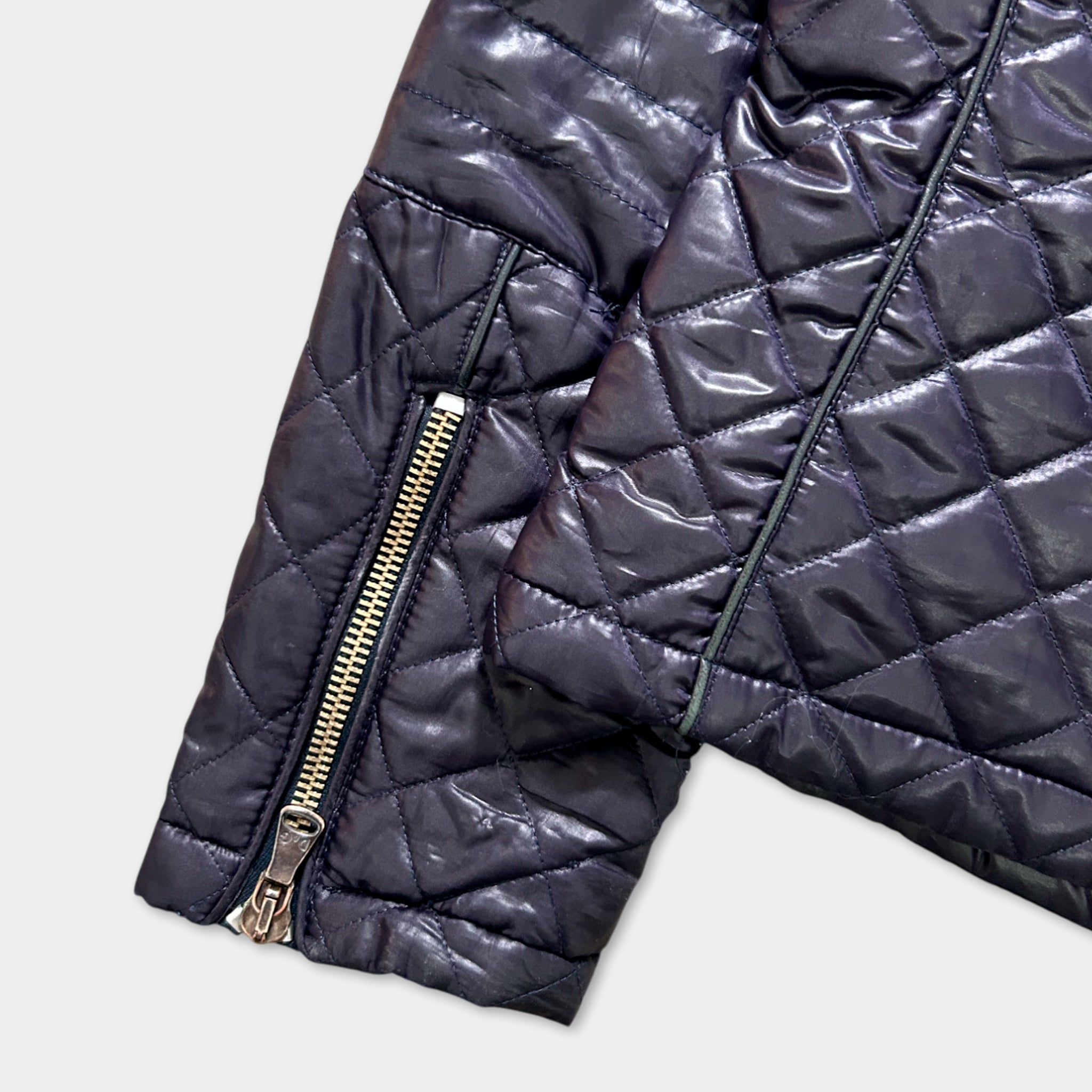 A close-up view of a dark quilted jacket with a zipper and pockets.