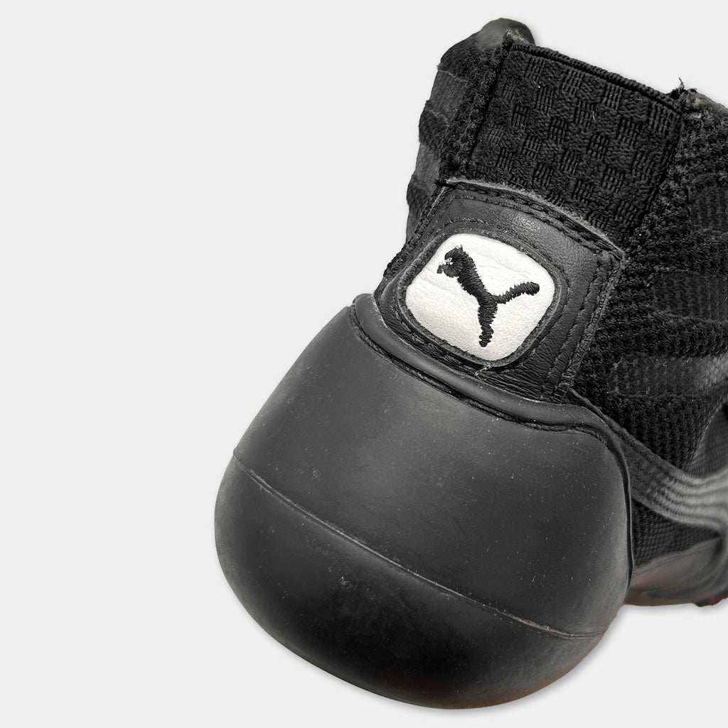 A close-up view of a black and white Puma sneaker, focusing on the upper part of the shoe.