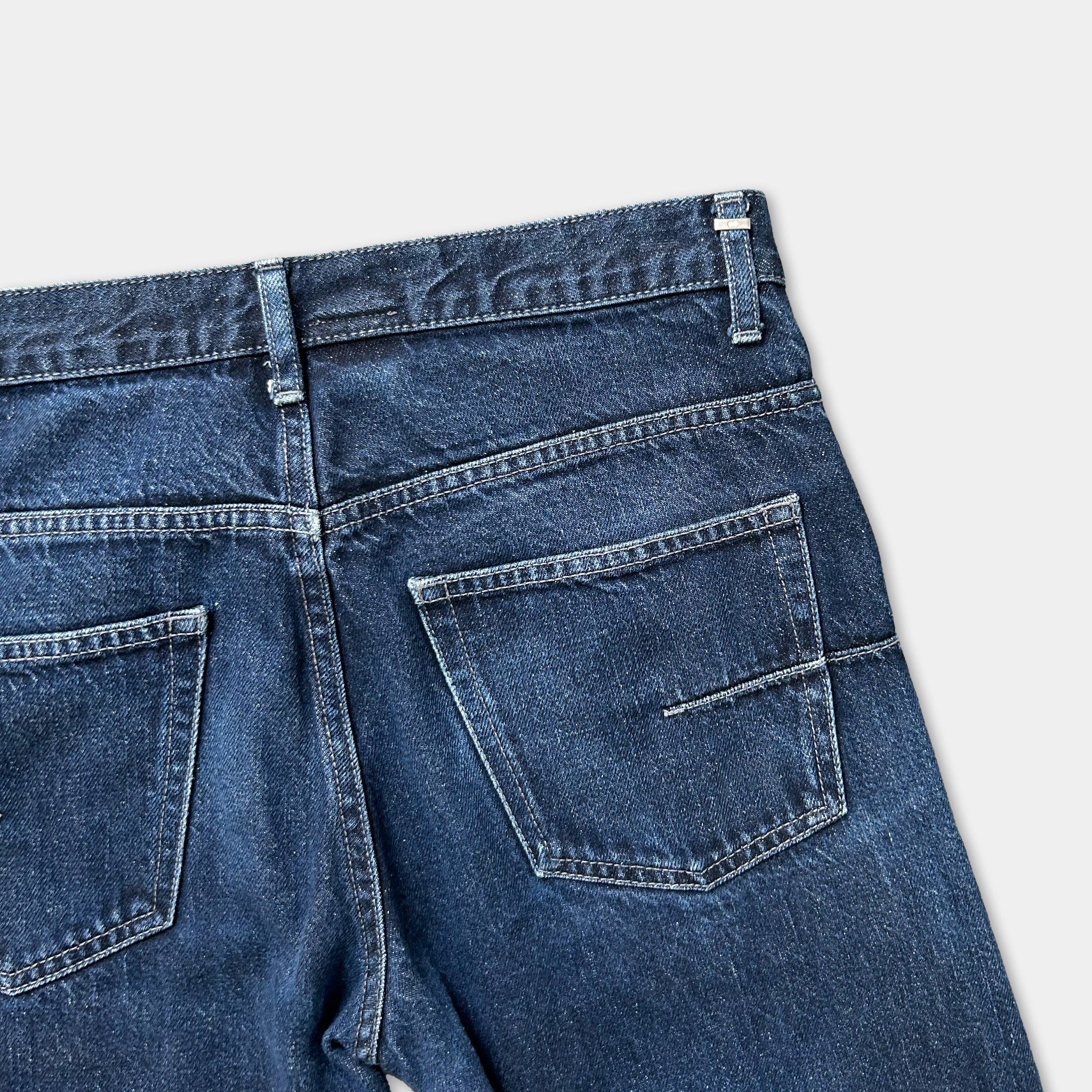 A pair of blue jeans with a pocket and zipper detail.