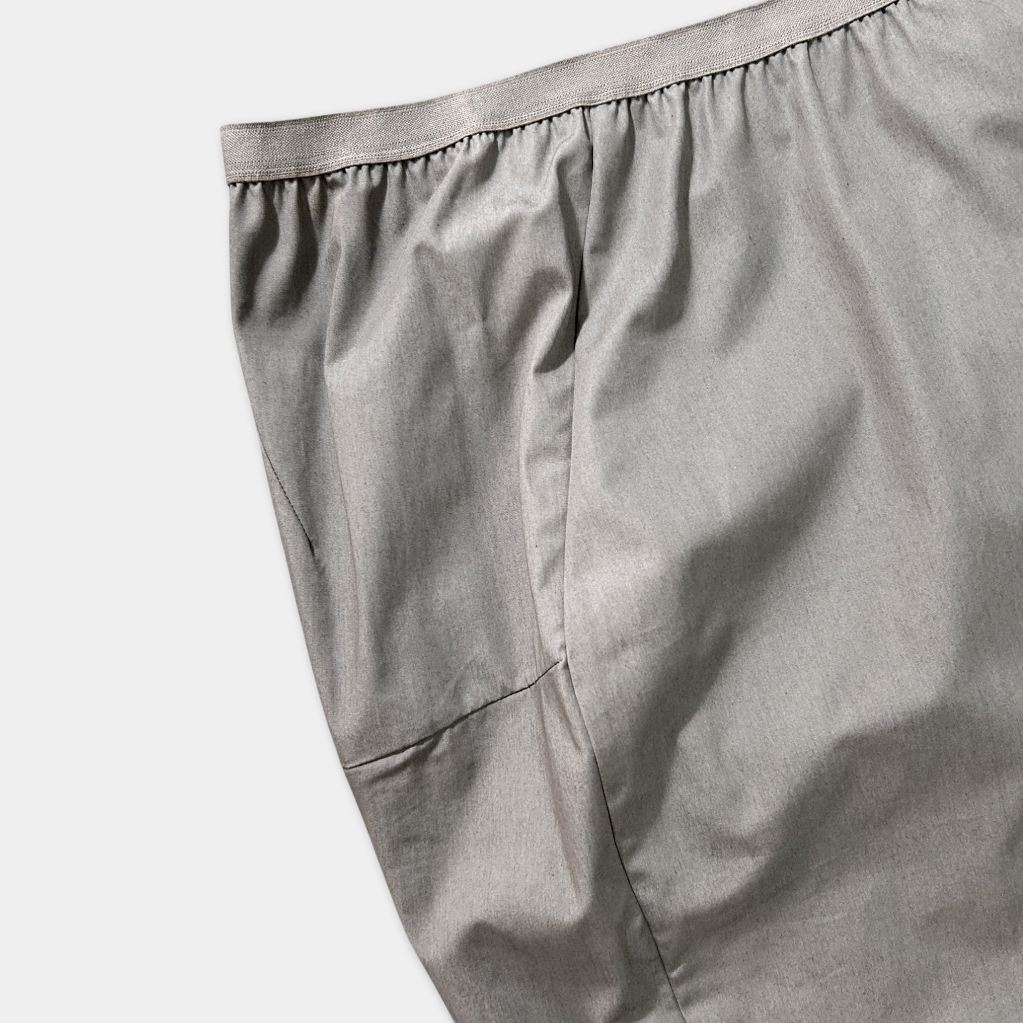 A close-up view of a gray skirt or garment, with a ruffled waistband and a small pocket visible.