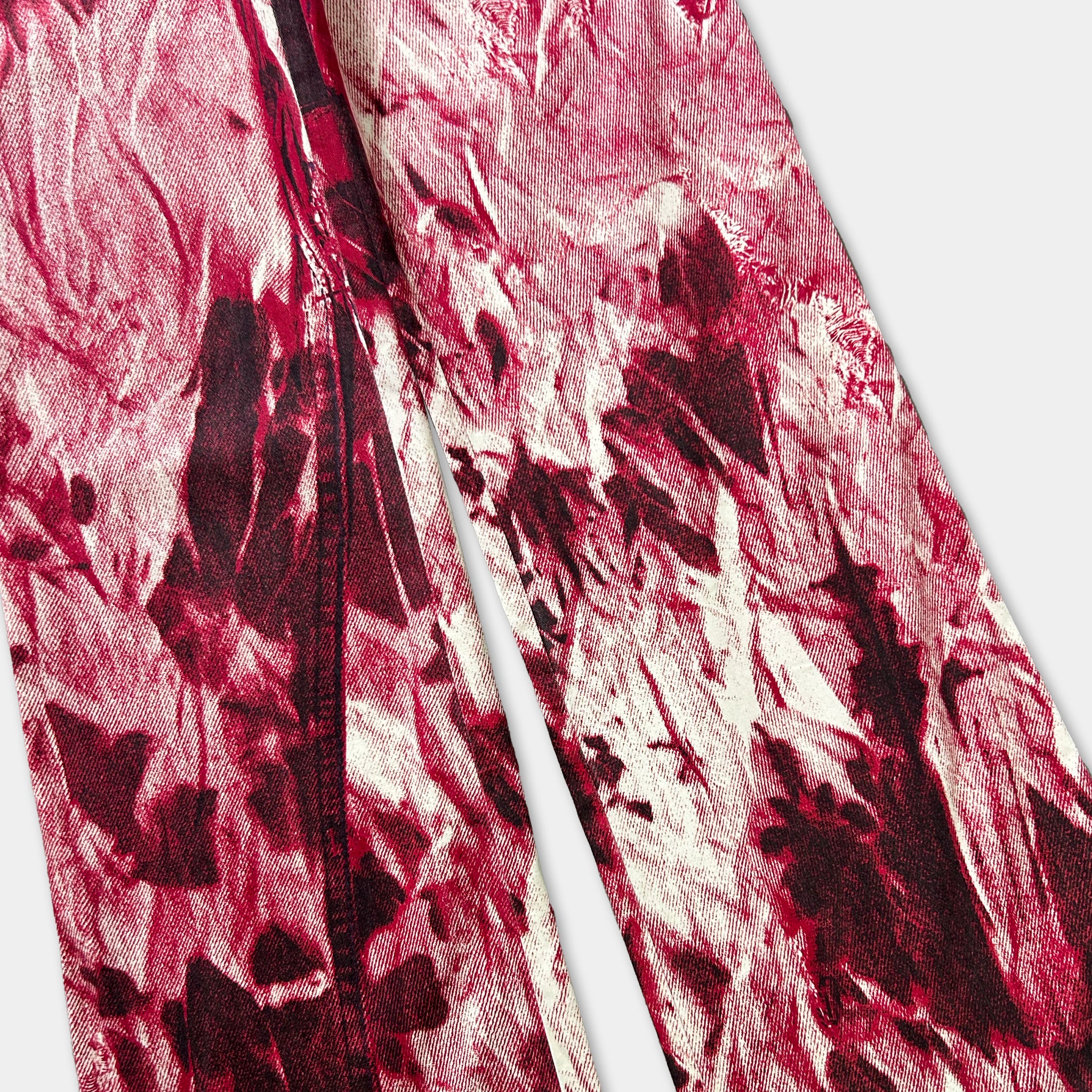 a close-up view of a pair of red and white patterned fabric, possibly jeans or pants, with a textured and abstract design.