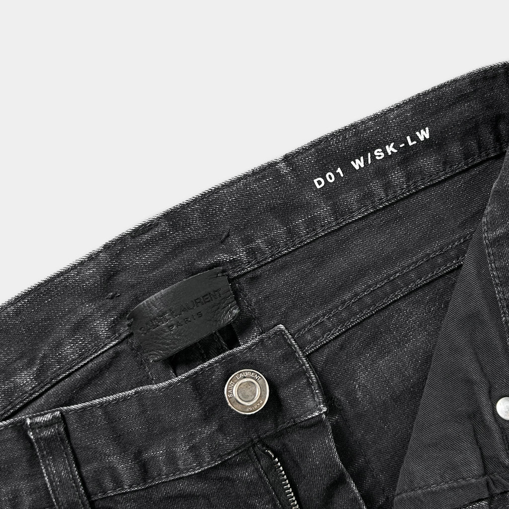 a close-up view of a pair of black jeans, with a label or tag attached to the waistband.