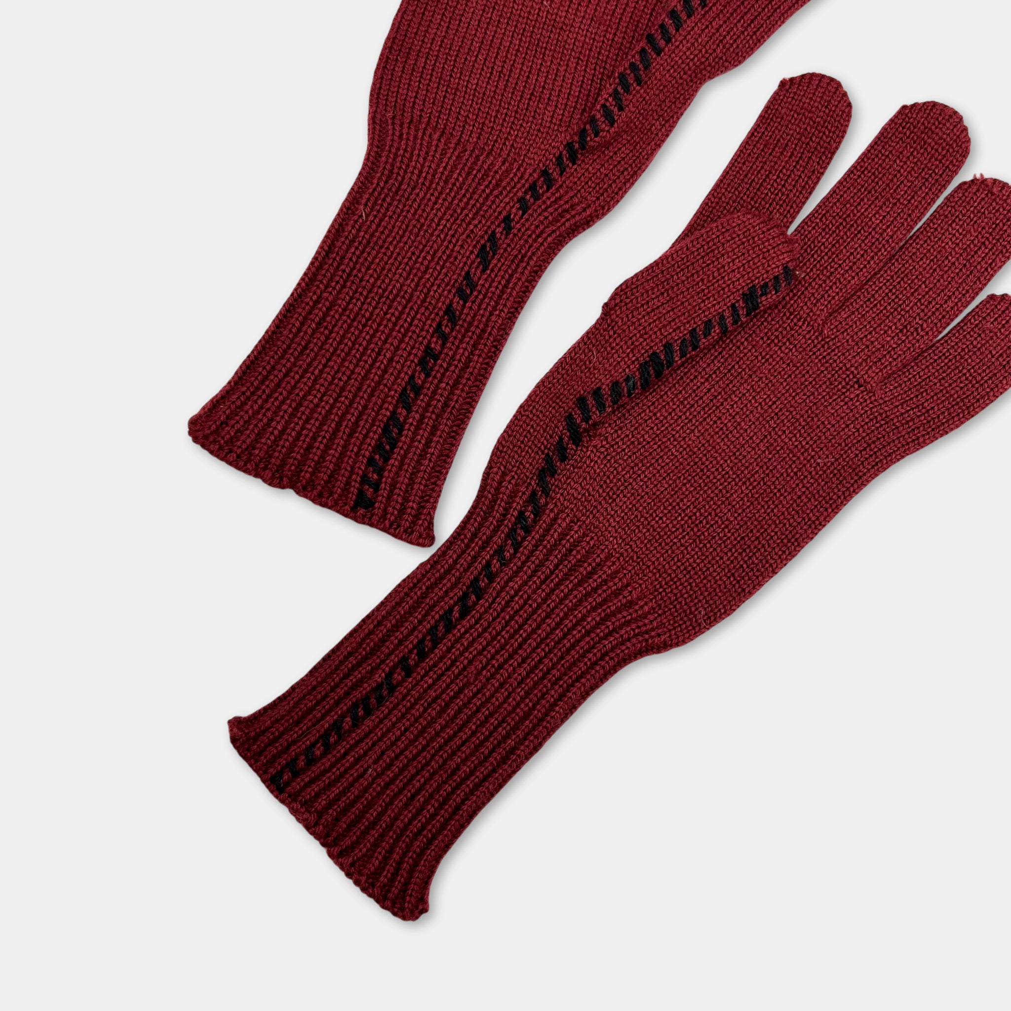 A pair of burgundy-colored knitted gloves with black stitching on the cuffs.