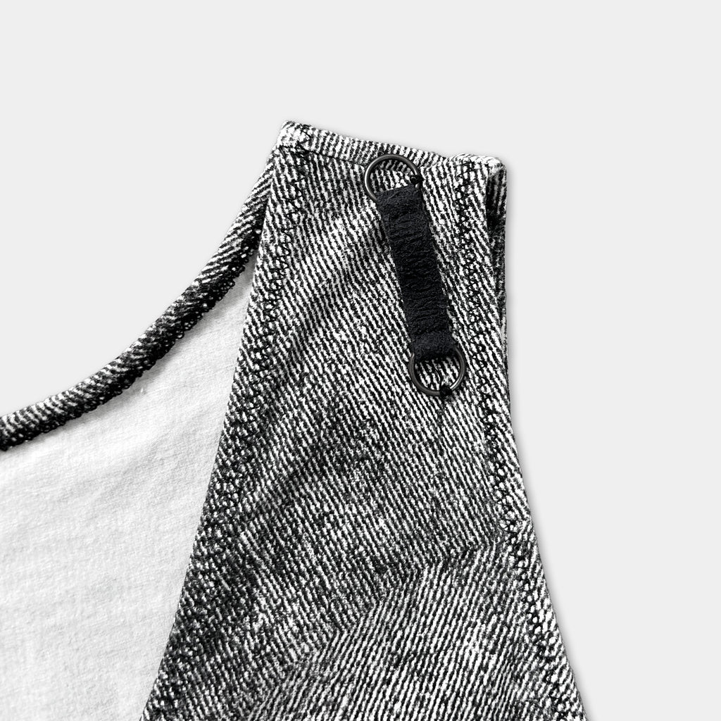 A close-up view of a black and white patterned fabric, possibly a dress or a shirt, with a black zipper pull and a black strap visible.