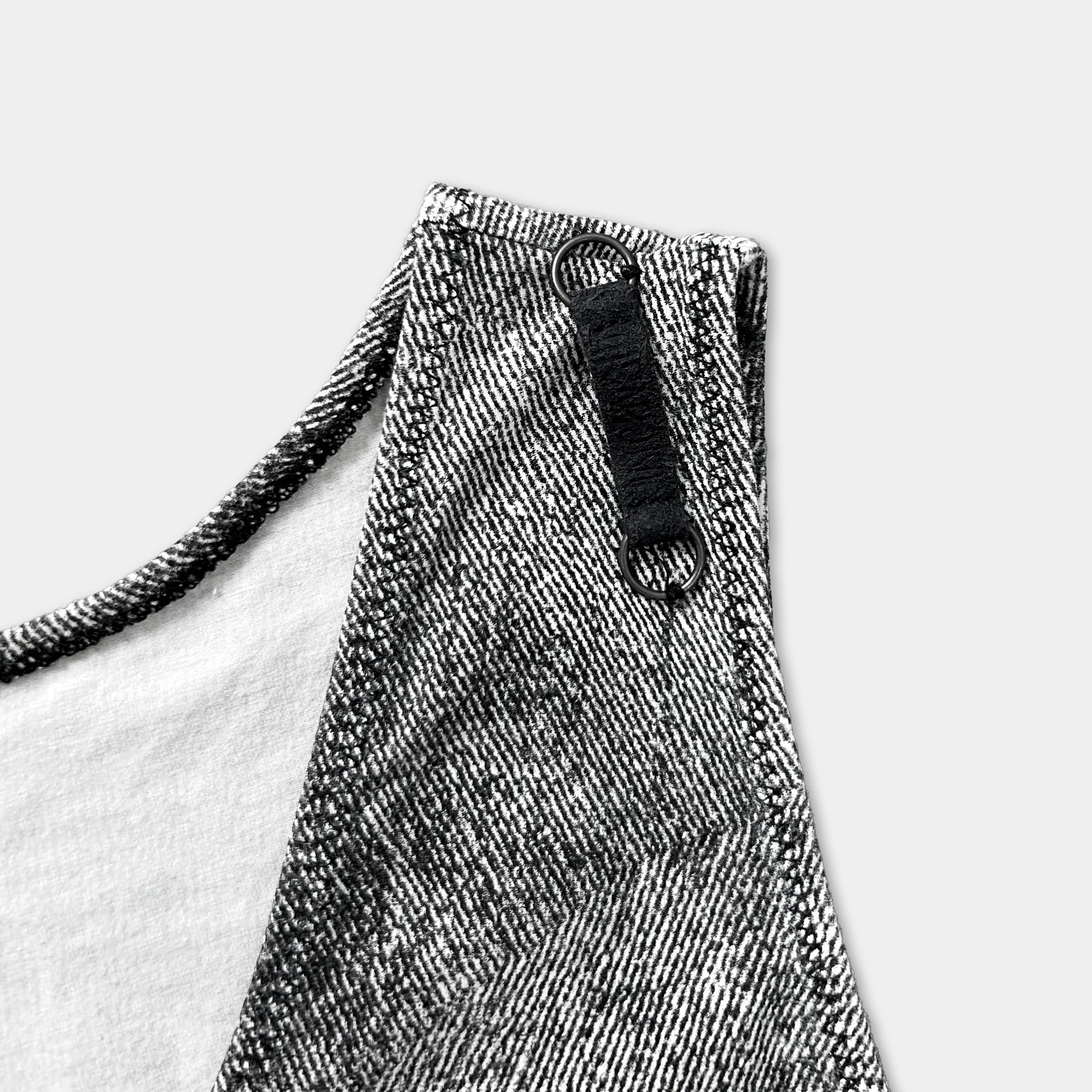 A close-up view of a black and white patterned fabric, possibly a dress or a shirt, with a black zipper pull and a black strap visible.
