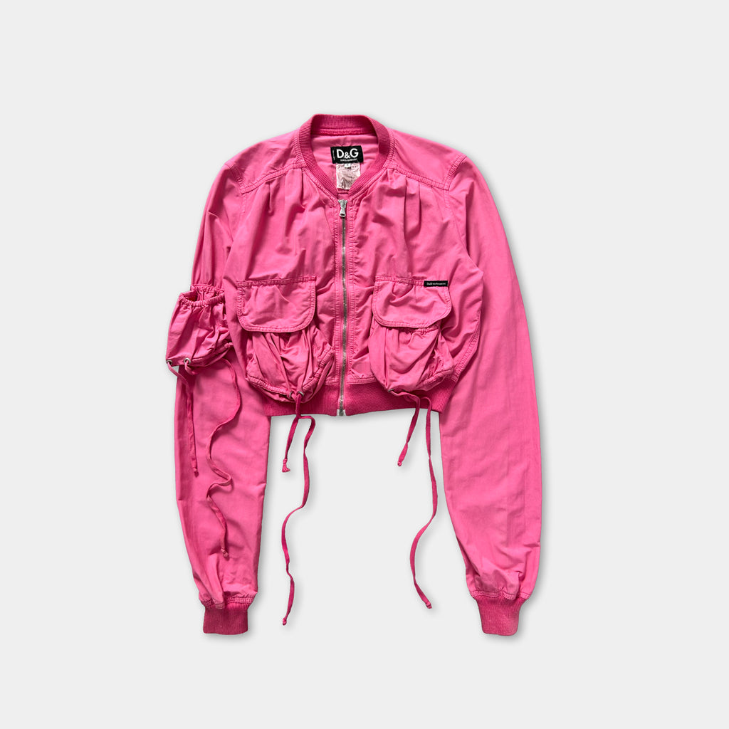 A bright pink jacket with multiple pockets and a tie at the back, displayed against a white background.