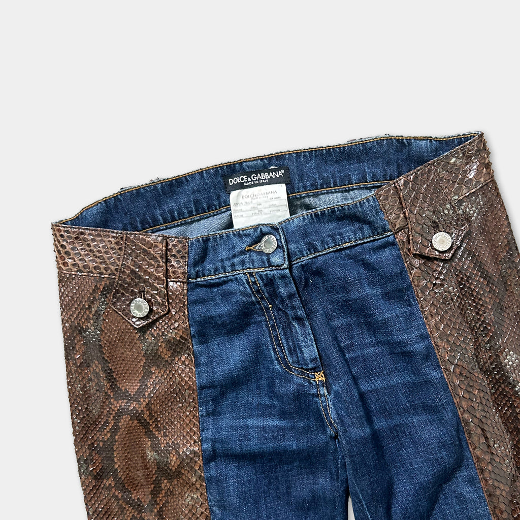 A pair of blue jeans with a brown snake skin-like pattern on the waistband and pockets.