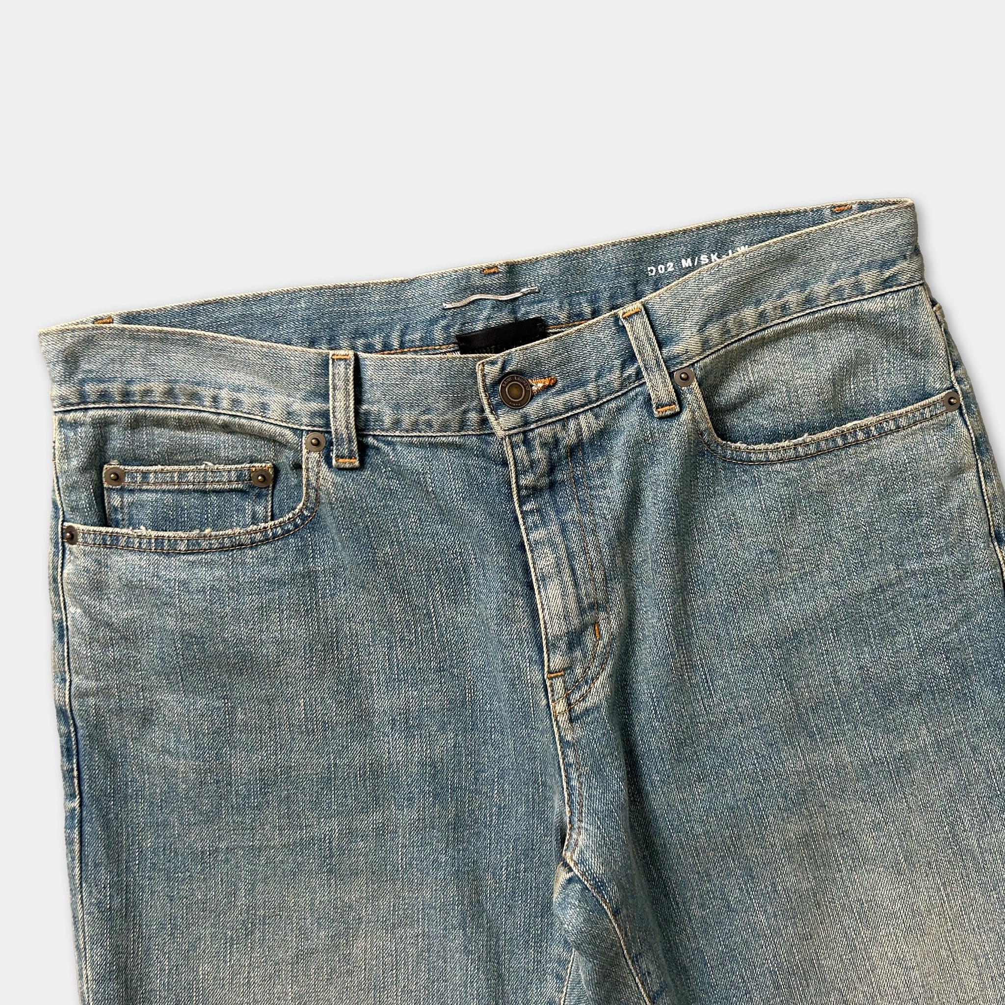 A pair of blue denim jeans with a button closure and pockets.