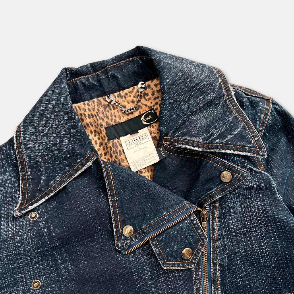 A close-up view of a denim jacket with a leopard print lining, showing the collar, zipper, and pockets.