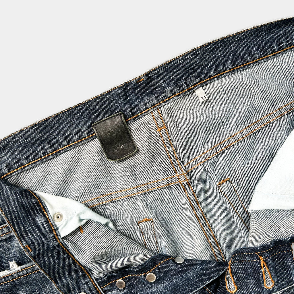 A close-up view of a pair of blue jeans, showing the zipper, pockets, and belt.