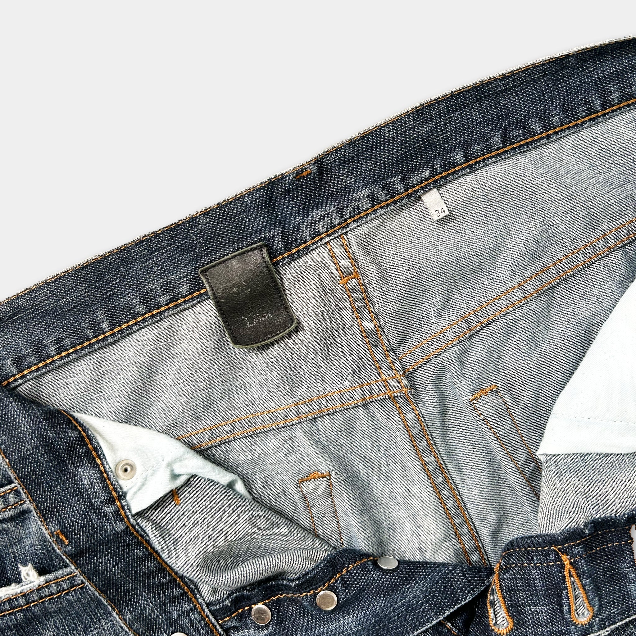 A close-up view of a pair of blue jeans, showing the zipper, pockets, and belt.