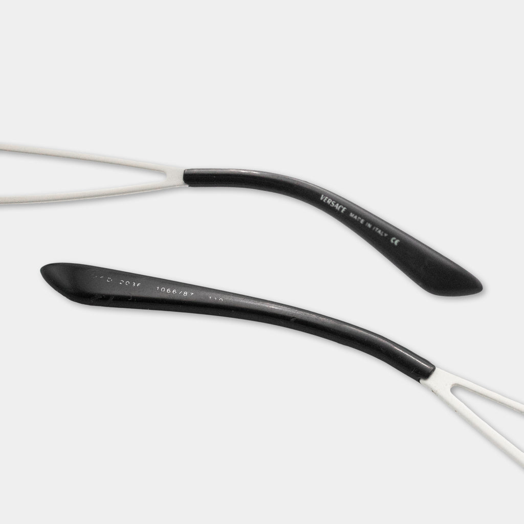 a pair of black and white eyeglasses with a curved black frame and white arms.