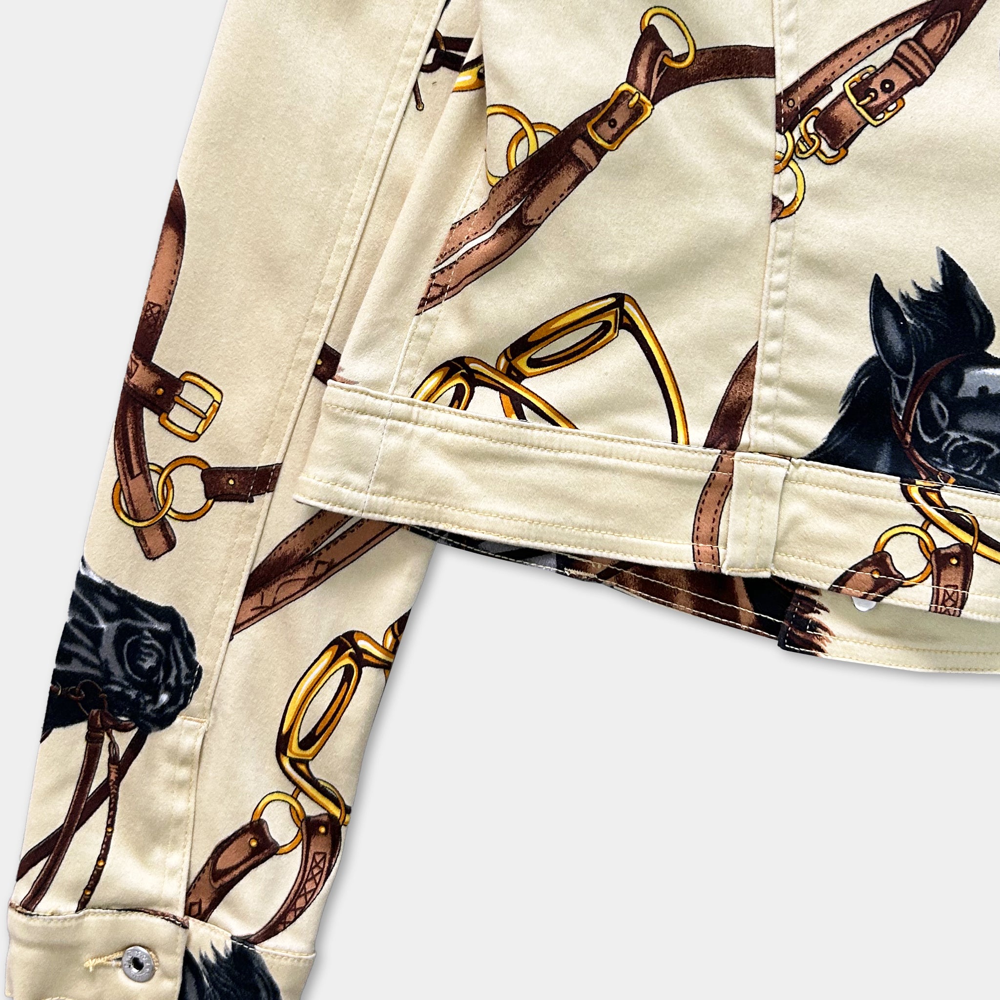 a close-up view of a beige jacket with a pattern of brown leather straps and a black horse on the front.