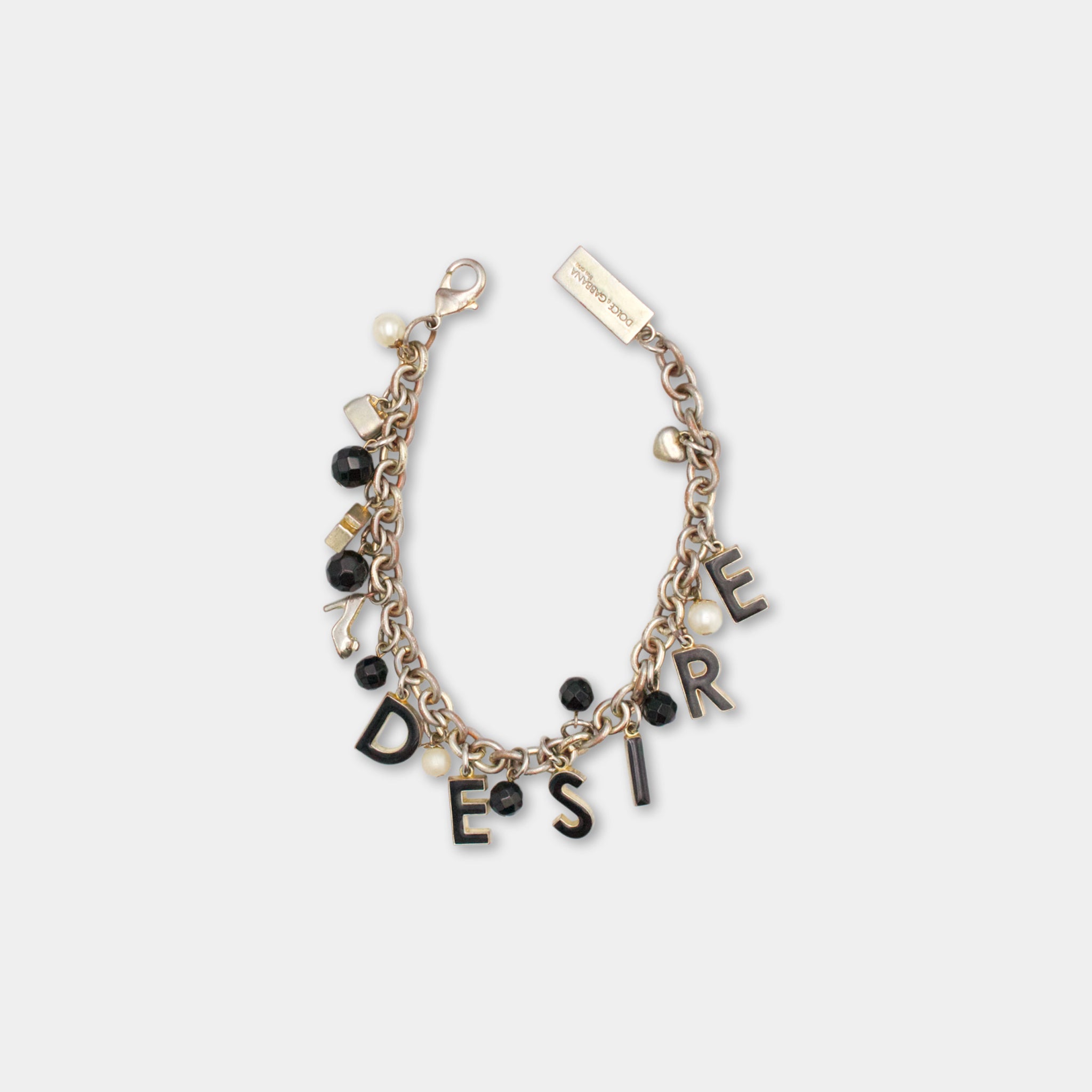 A bracelet with the word "DESIRE" spelled out in black letters, surrounded by various charms and beads in shades of black, white, and gold.