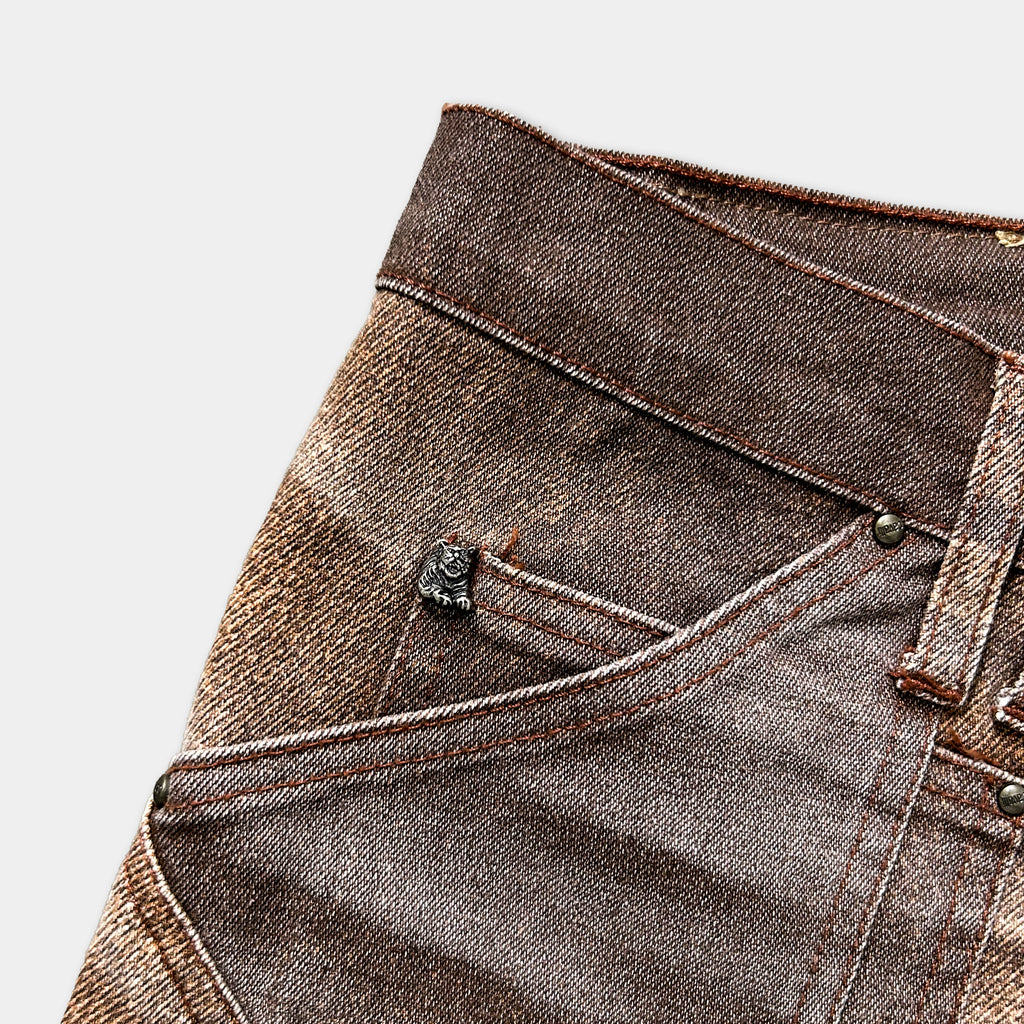 A close-up view of a pair of brown and tan jeans, showing the pocket and zipper detail.