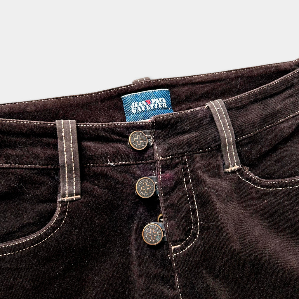 A close-up view of a pair of dark brown, button-up jeans with a label on the waistband.