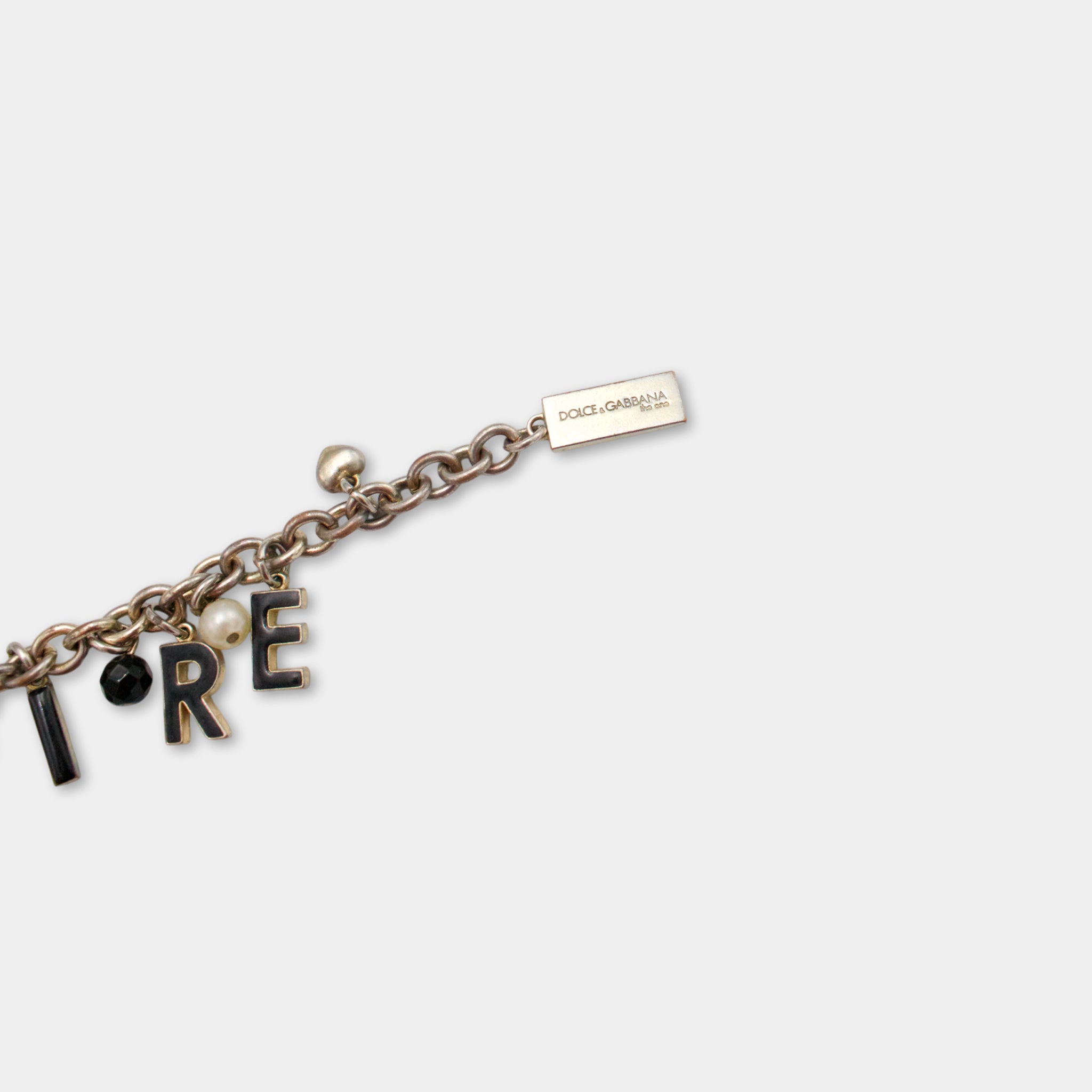 A bracelet with the word "RE" on it, along with other charms and a tag.