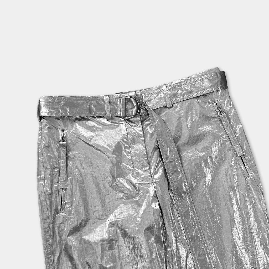 A pair of shiny, metallic silver pants with a belt and zipper details.