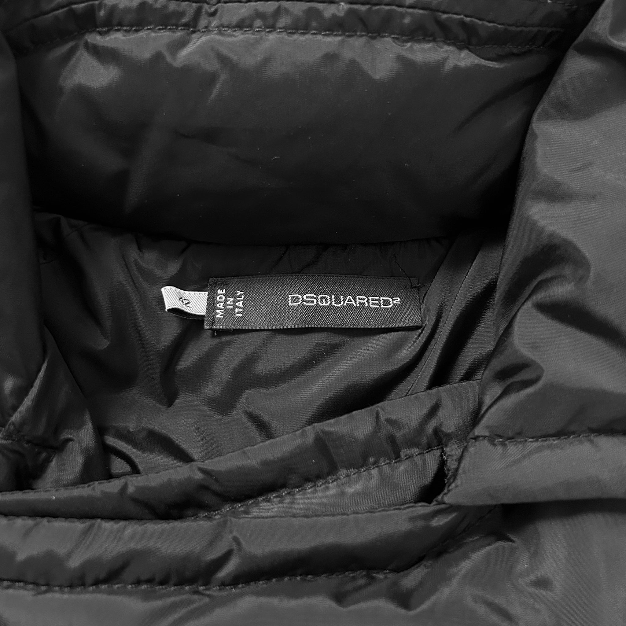 A close-up view of a black puffy jacket, showing the label "OSQUIRED" and the brand name "D'SQUARED" printed on it.
