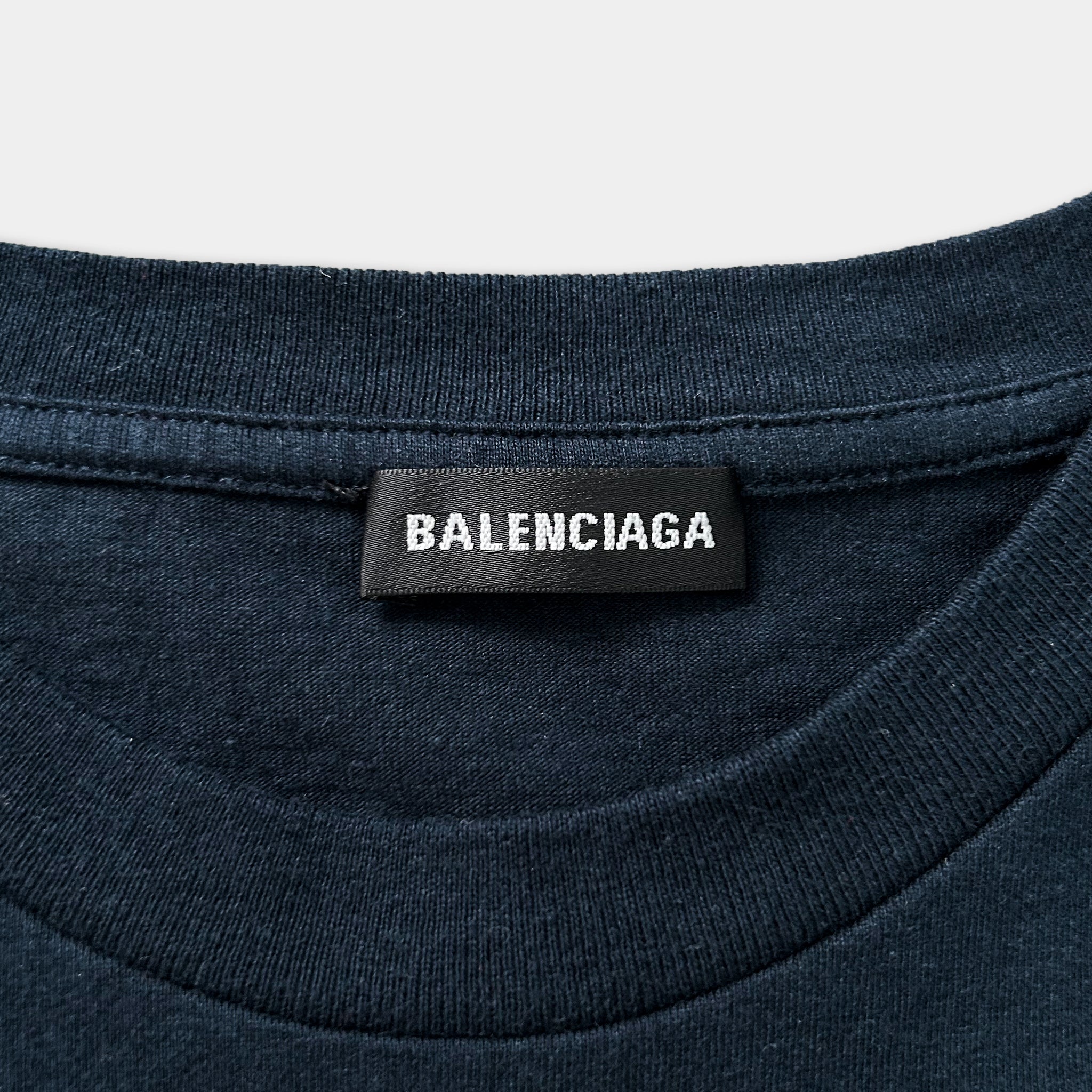 A close-up view of a dark blue t-shirt with a black label that reads "BALENCIA" prominently displayed on the shirt.