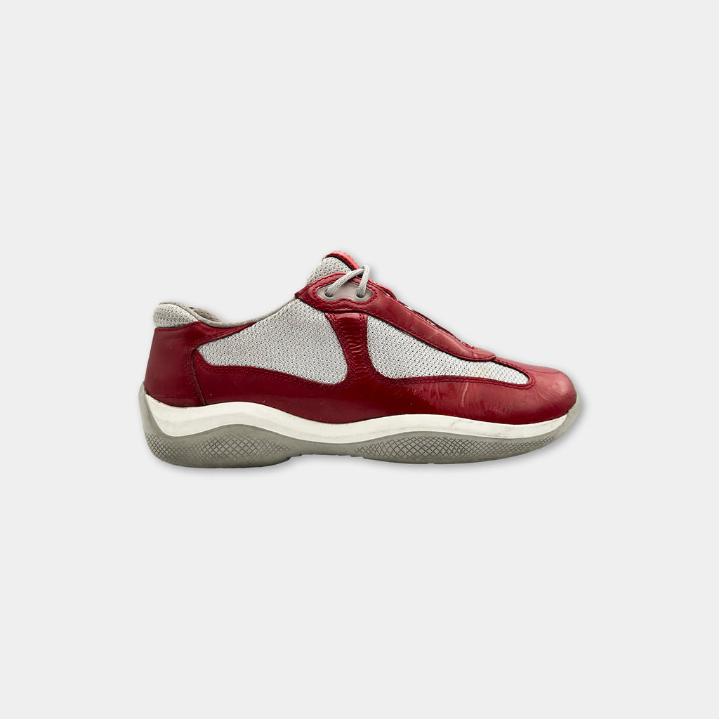 A red and white sneaker with a white sole and a white mesh panel on the side.