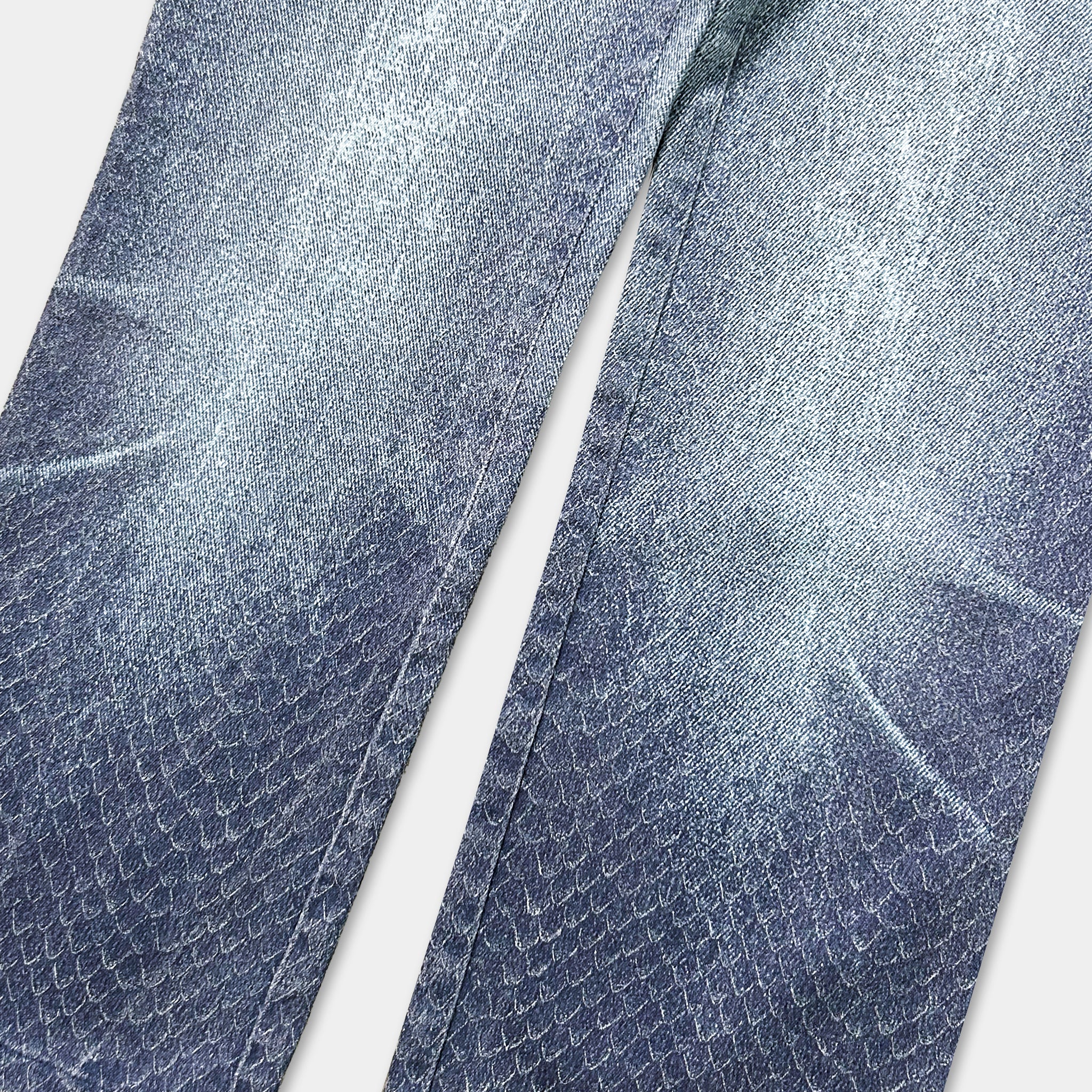 A close-up view of a pair of blue jeans with a distinctive snake skin pattern.