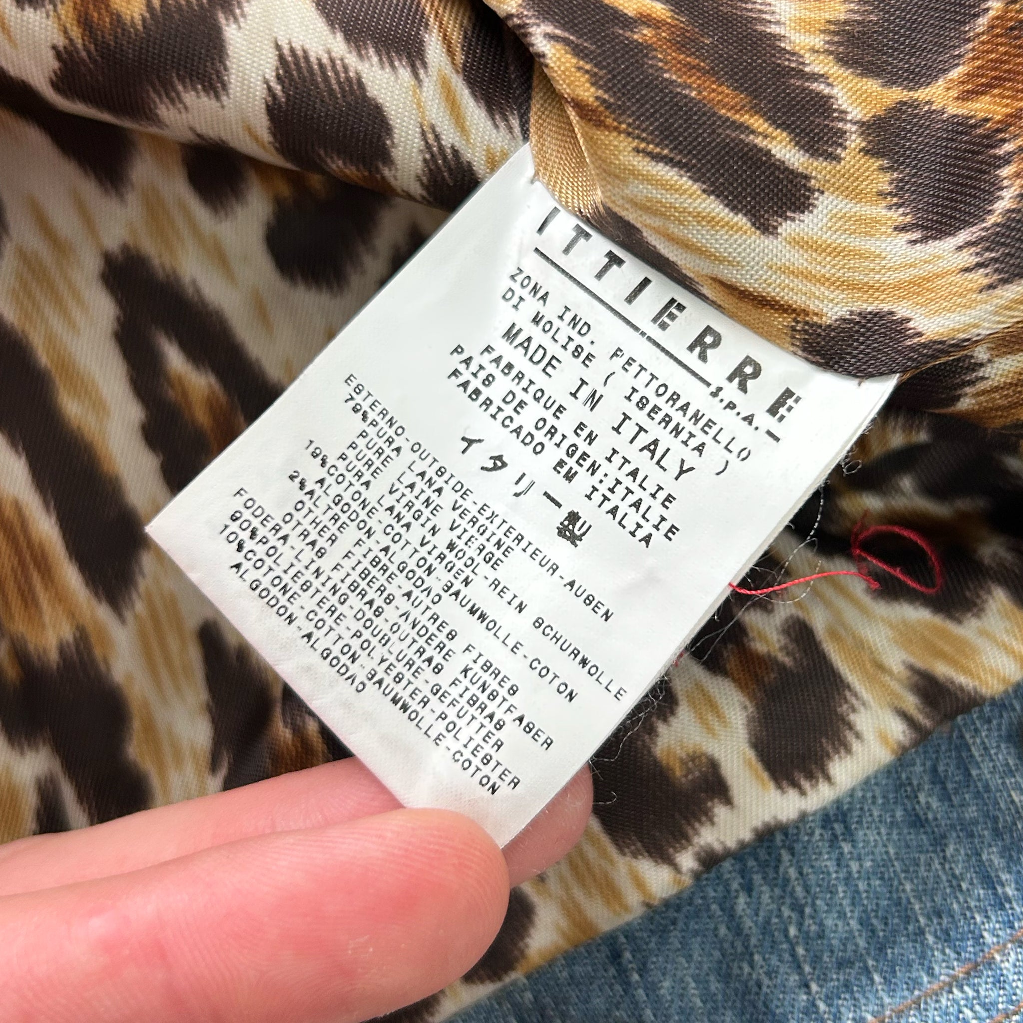A close-up of a hand holding a label with text on it, against a leopard print background.