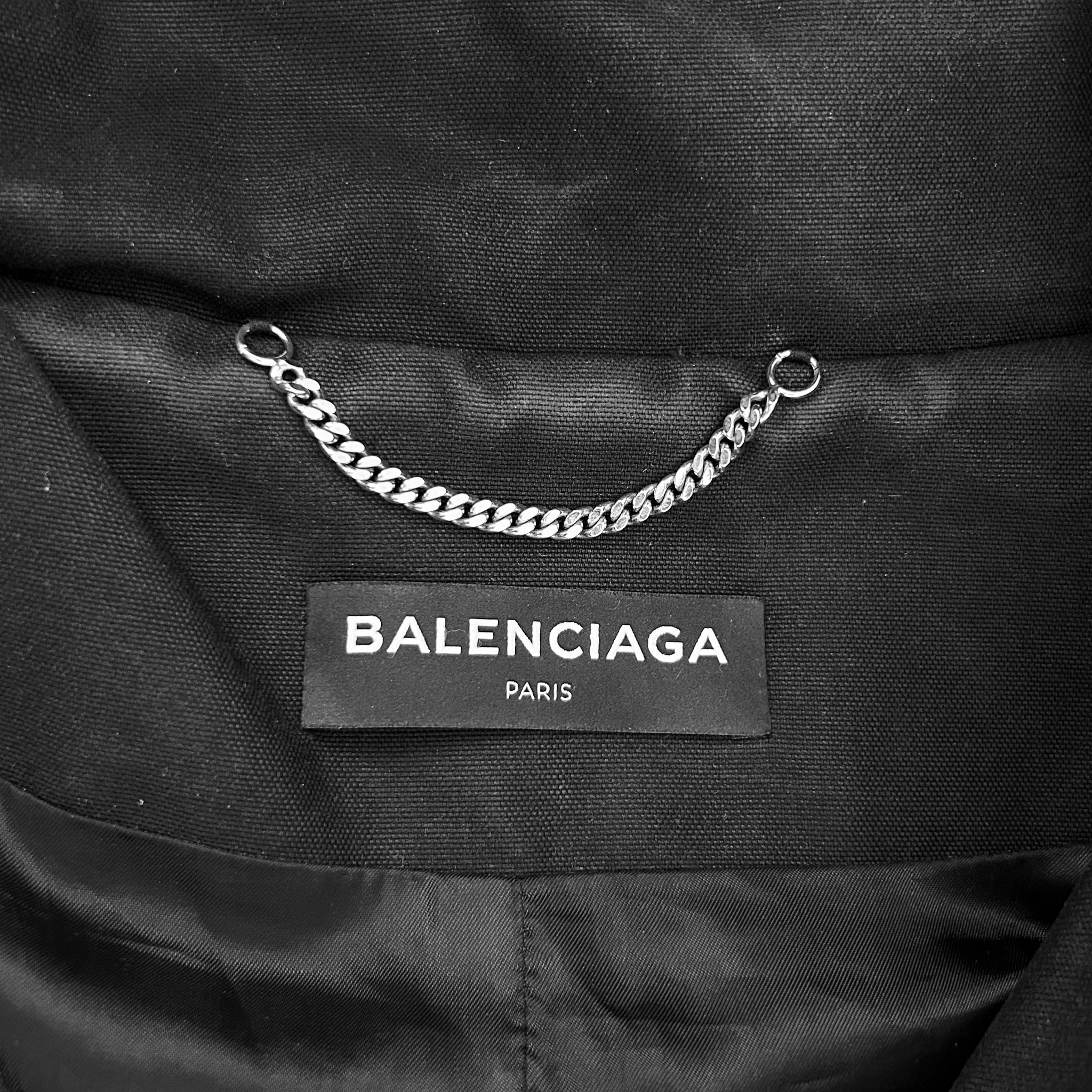 A close-up view of a black fabric with a silver chain attached to it, and a label that reads "BALENCIAGA PARIS".