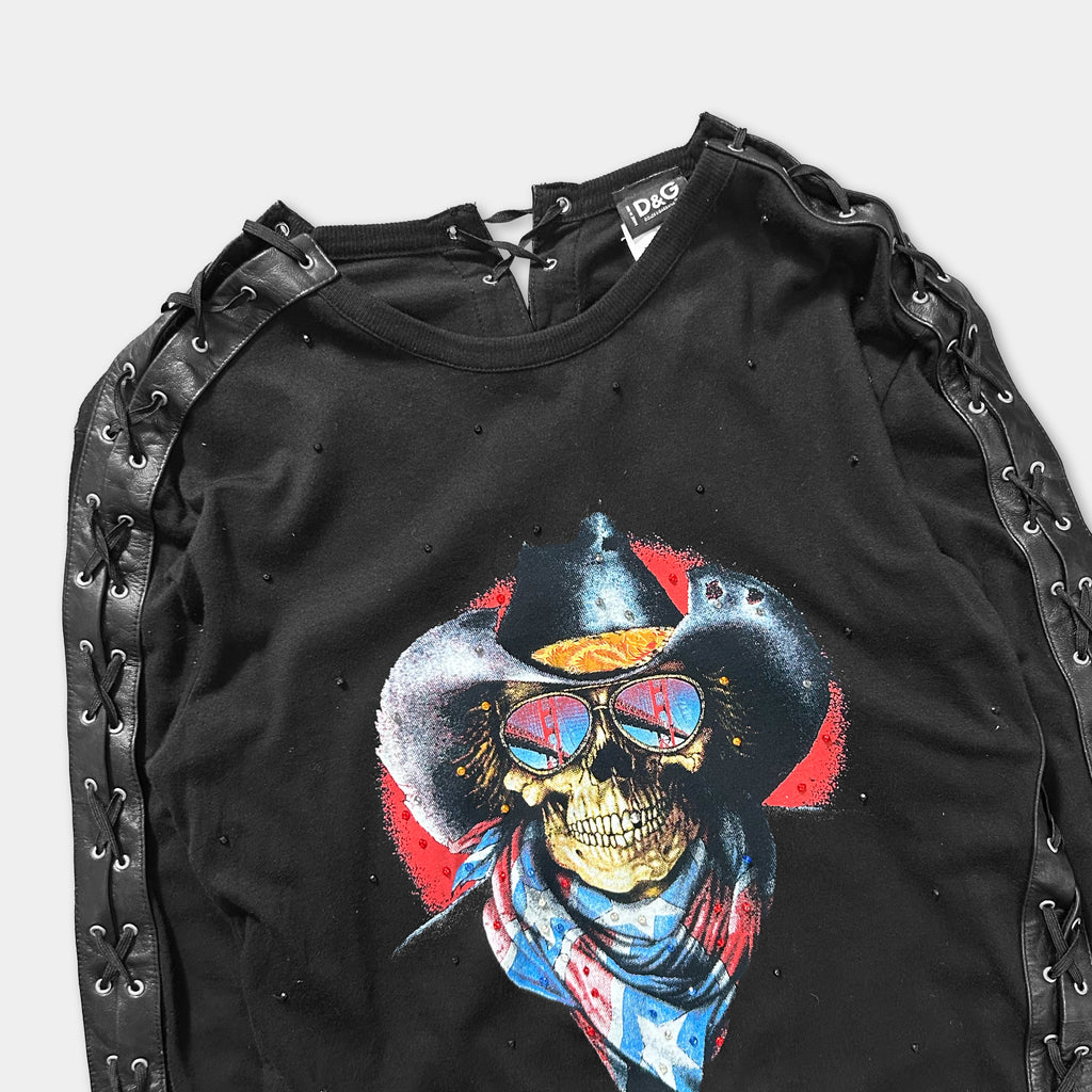 A black shirt with a graphic design featuring a skull wearing sunglasses and a cowboy hat, along with a red and blue scarf.