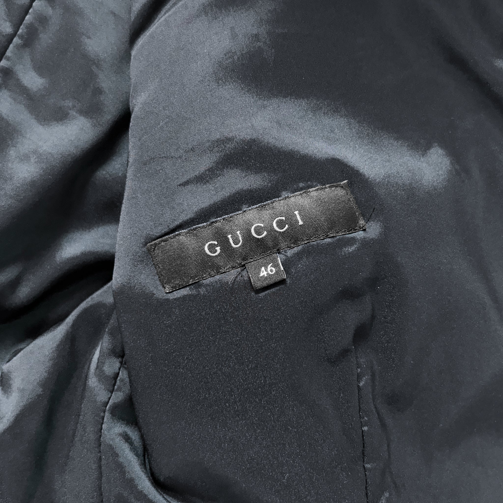 a close-up view of a black Gucci jacket, with the brand's name and a number 46 visible on the label.
