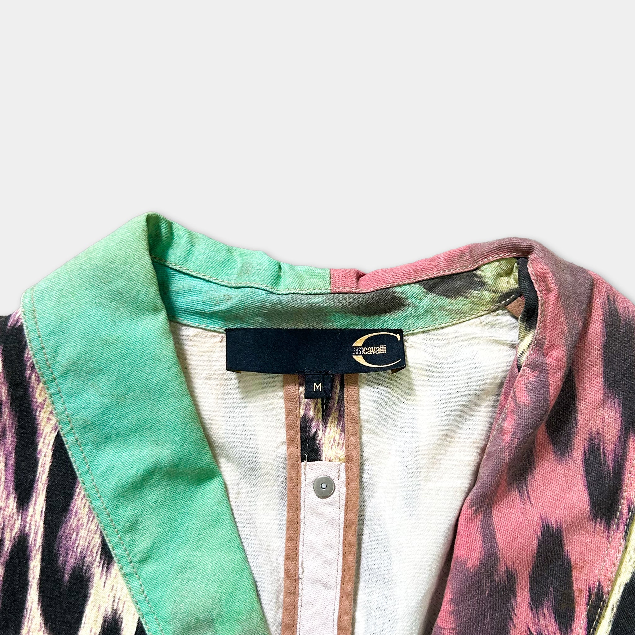 a close-up view of a colorful, patterned jacket with a collar and a label on the collar.