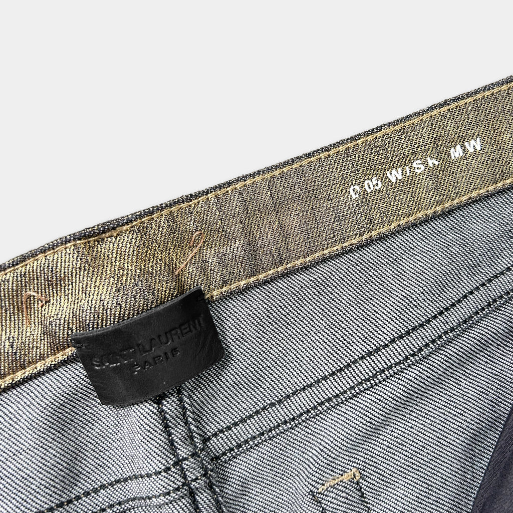 a close-up view of a pair of gray jeans with a black label attached to the waistband.