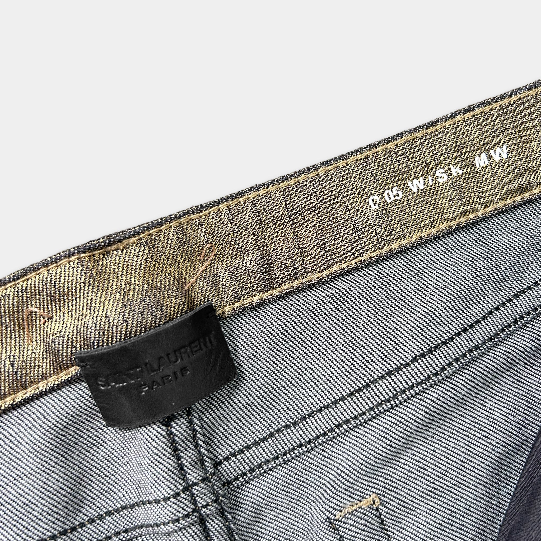 a close-up view of a pair of gray jeans with a black label attached to the waistband.