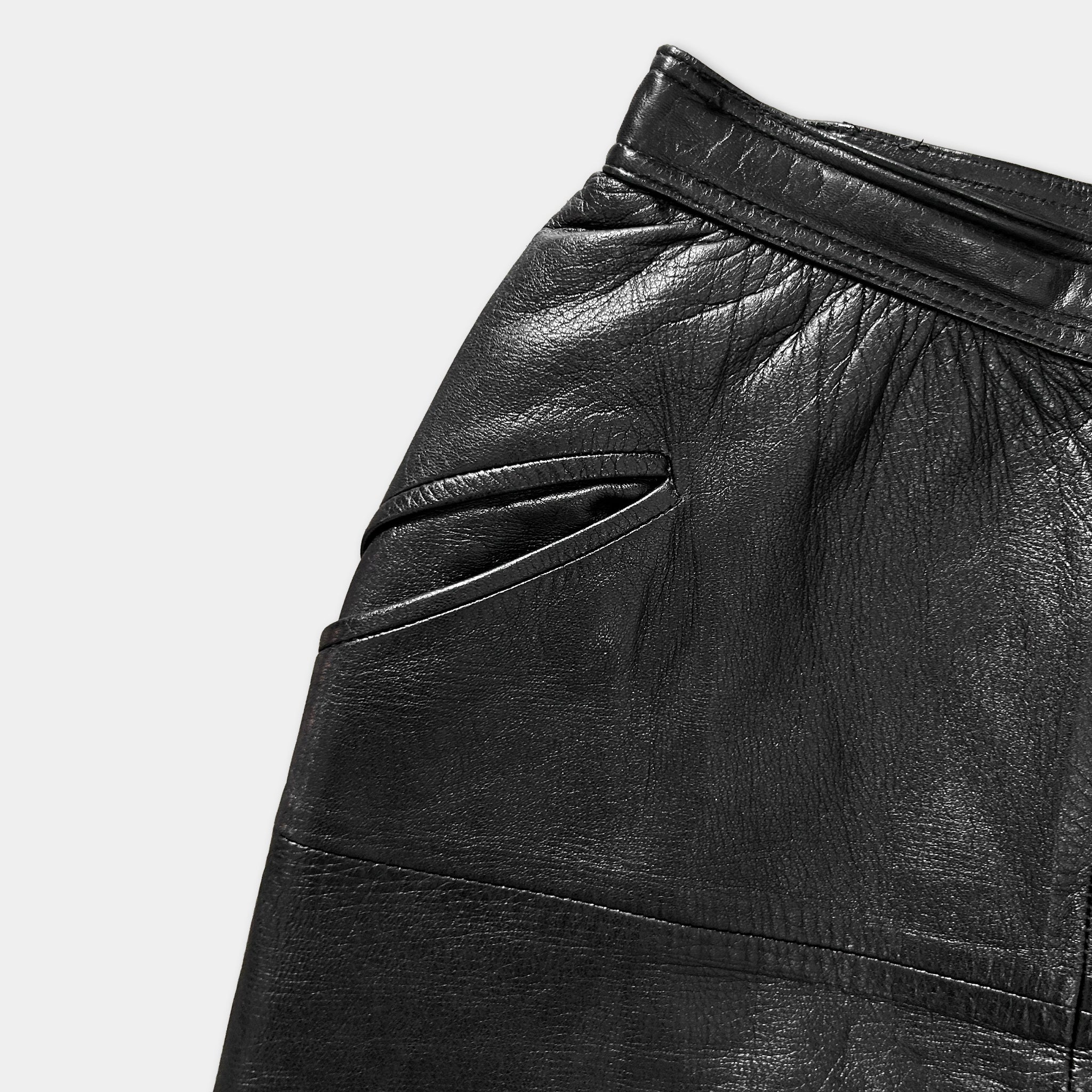 A close-up view of a pair of black leather shorts, showing the fabric and details of the garment.