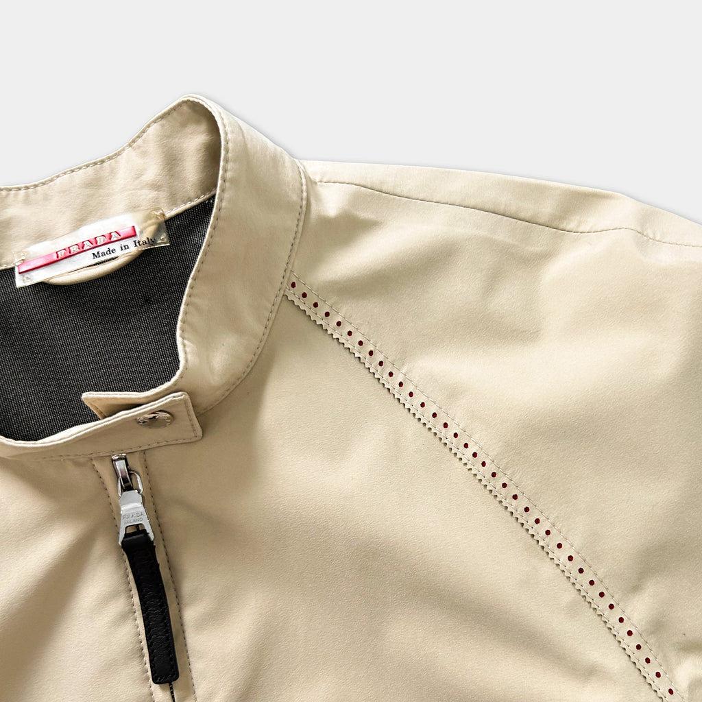 A beige jacket with a zipper and a label on the collar.