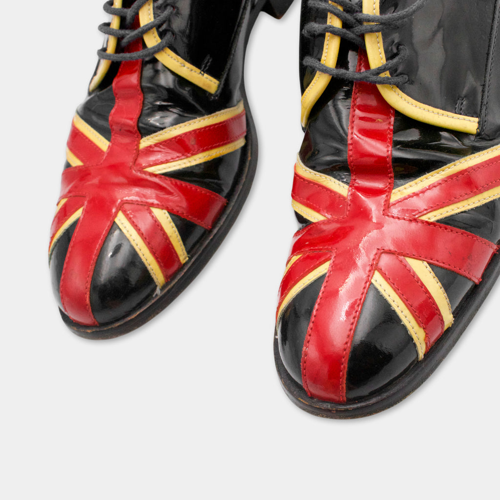 A pair of black and red shoes with a distinctive red and yellow British flag design.