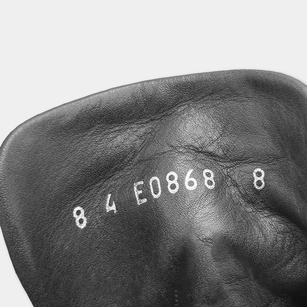 A close-up black and white image of a leather object with the numbers "84 E0868" printed on it.