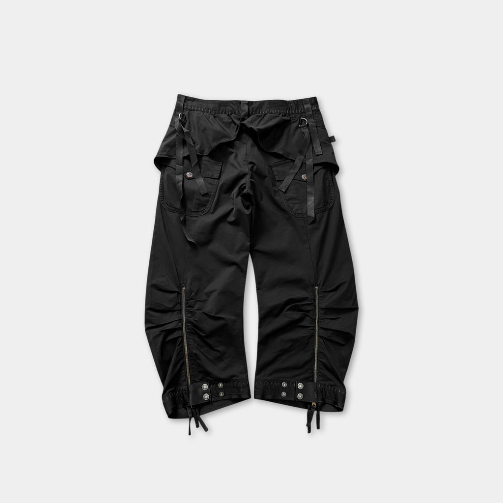 A pair of black cargo pants with multiple pockets and zippers.