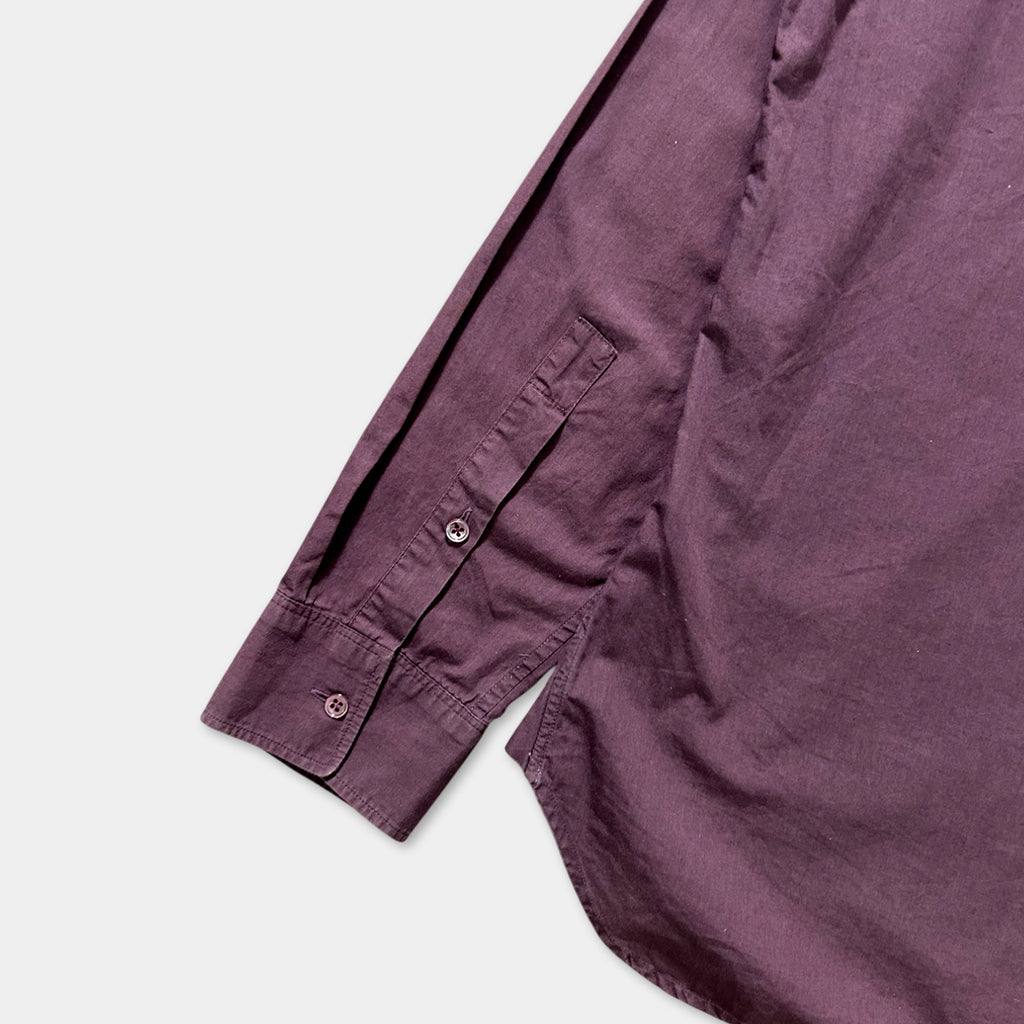 A close-up view of a purple shirt with a button and a pocket on the sleeve.