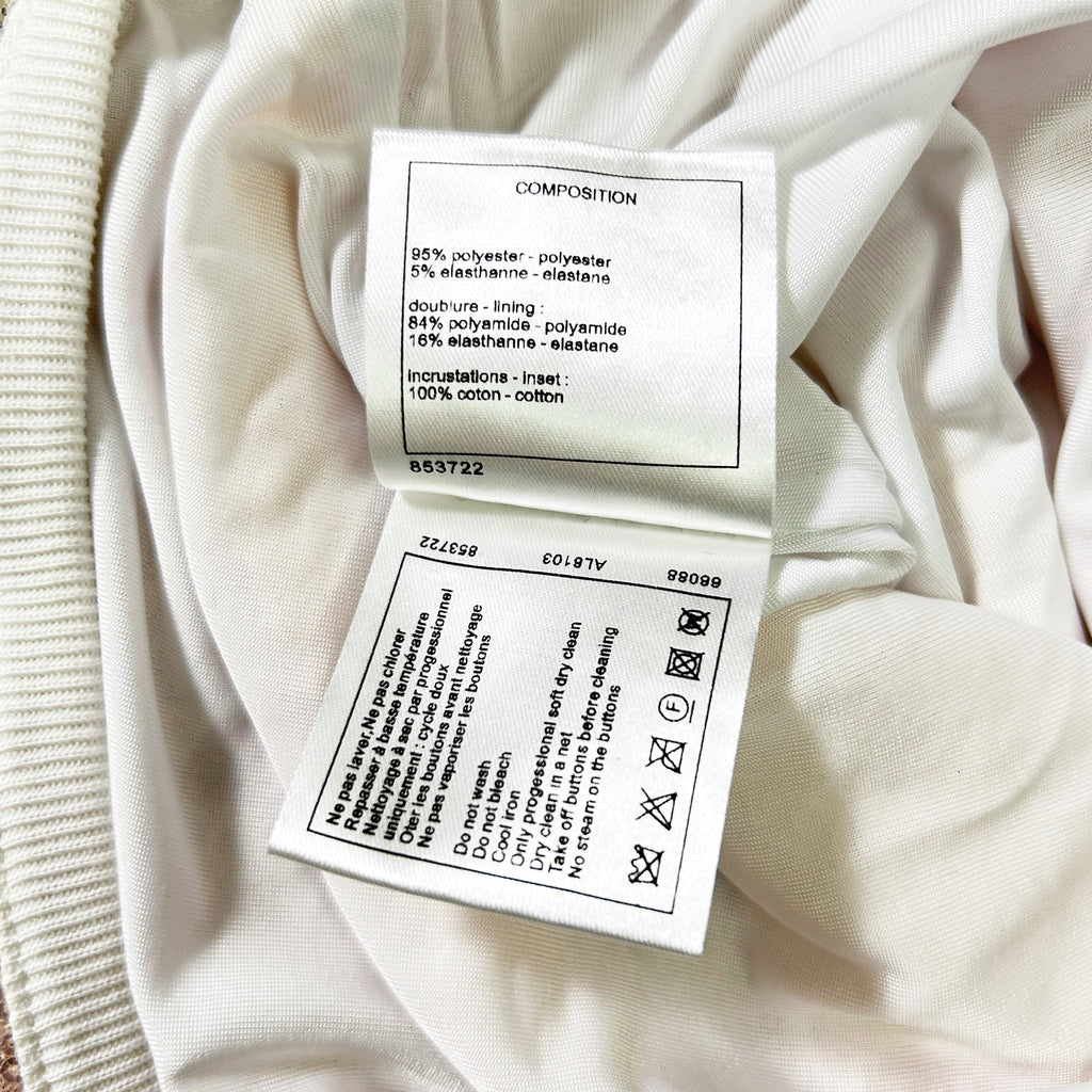 a close-up view of a white fabric, possibly a garment or textile, with a label attached to it. The label provides information about the composition of the fabric, including details about the type of plastic used and the percentage of plastic in the fabric.