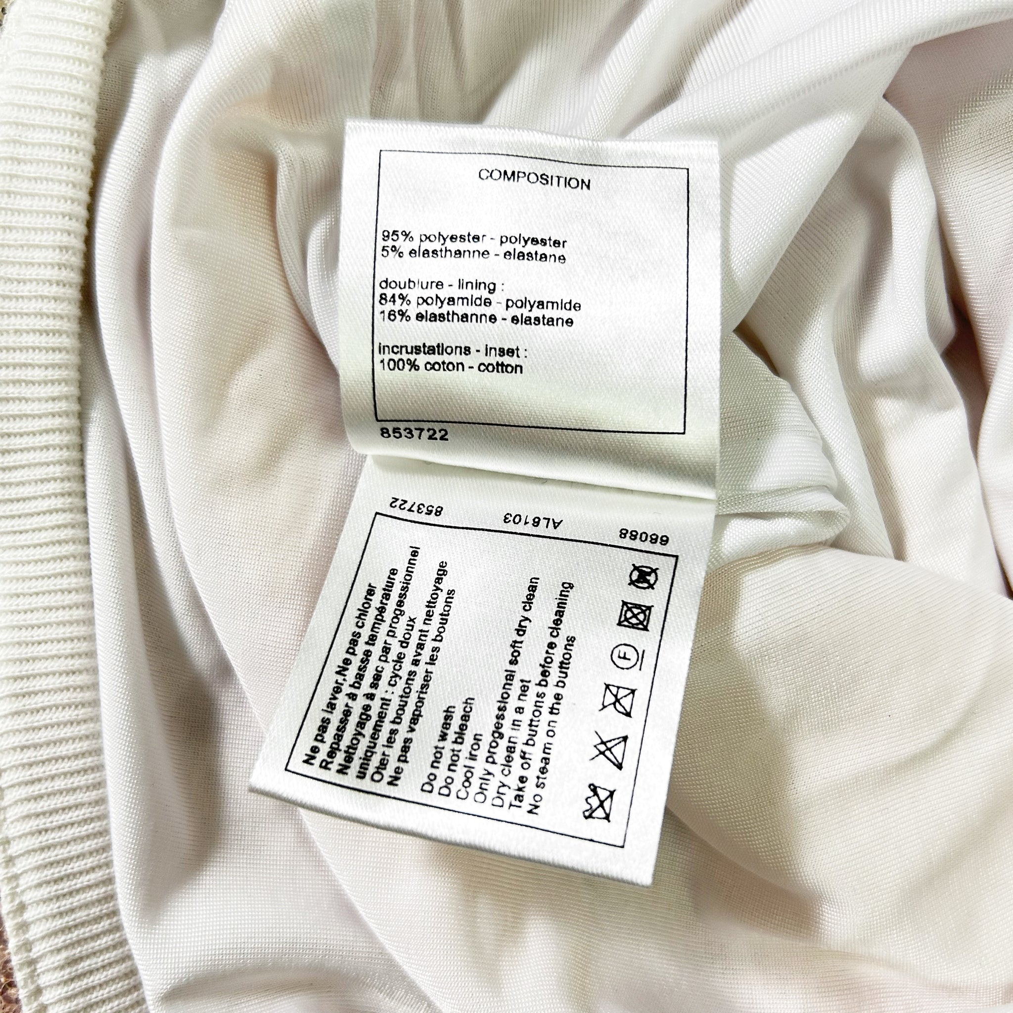 a close-up view of a white fabric, possibly a garment or textile, with a label attached to it. The label provides information about the composition of the fabric, including details about the type of plastic used and the percentage of plastic in the fabric.