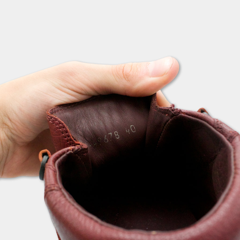 A hand is holding a red leather shoe with the sole visible, showing the number "40" inside the shoe.