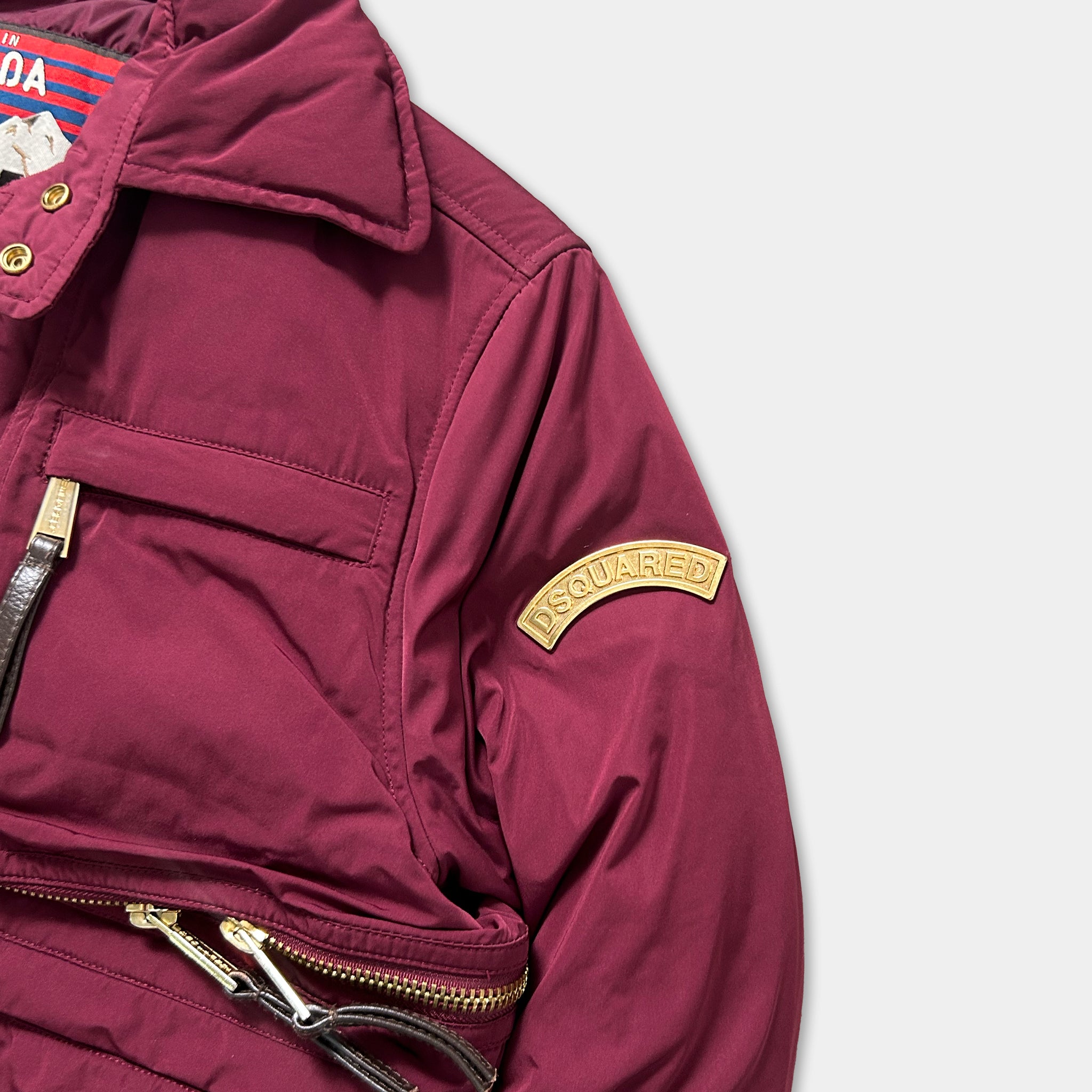 A close-up view of a burgundy jacket with a gold patch on the left arm, featuring the word "DOUGLED" in gold lettering.