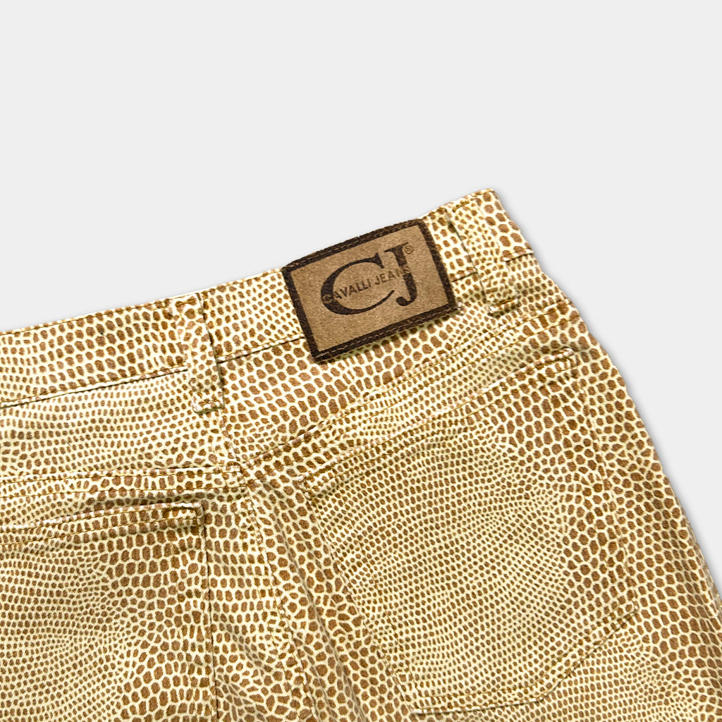 a pair of tan-colored jeans with a distinctive pattern resembling a snake or lizard. The jeans have a label or patch on the waistband that reads "CALVIN JEAN".