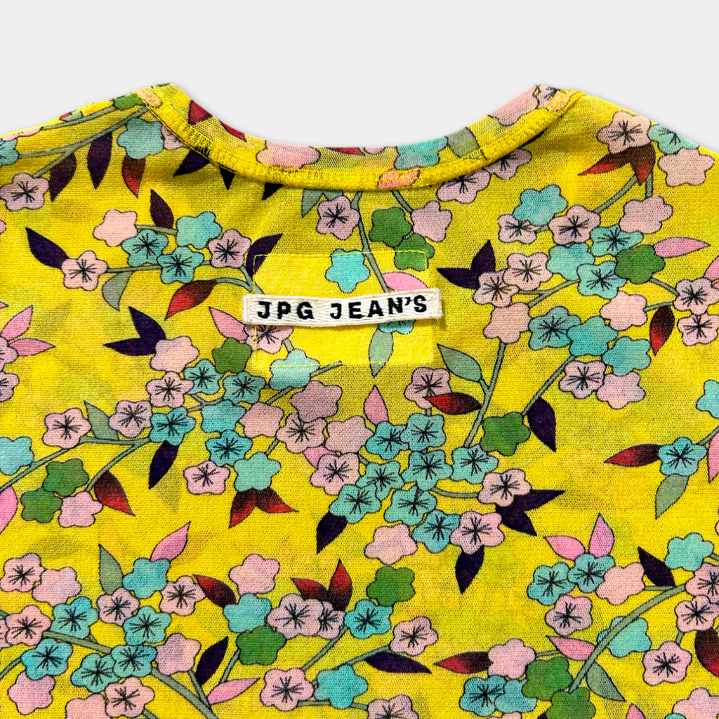 a yellow floral print shirt with a white label on the collar.